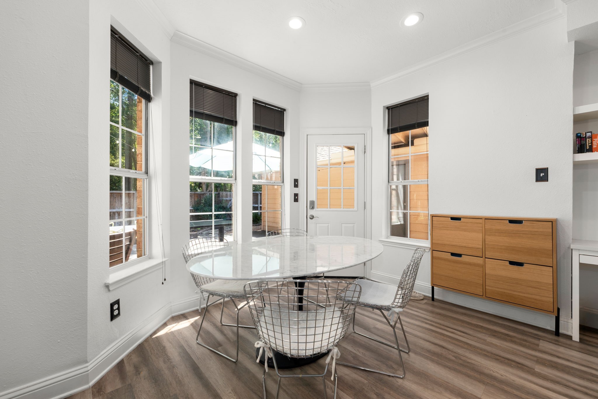 Bright breakfast nook featuring large windows, complemented by elegant wood-look flooring and a convenient storage unit.