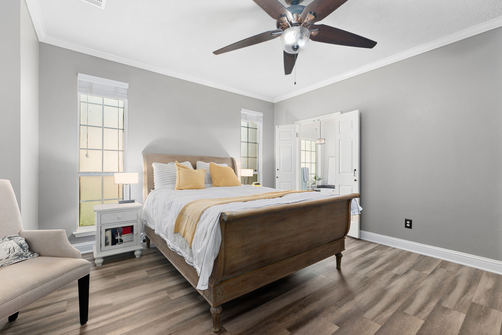 Bright and inviting bedroom featuring a modern ceiling fan, and large windows that fill the space with natural light.