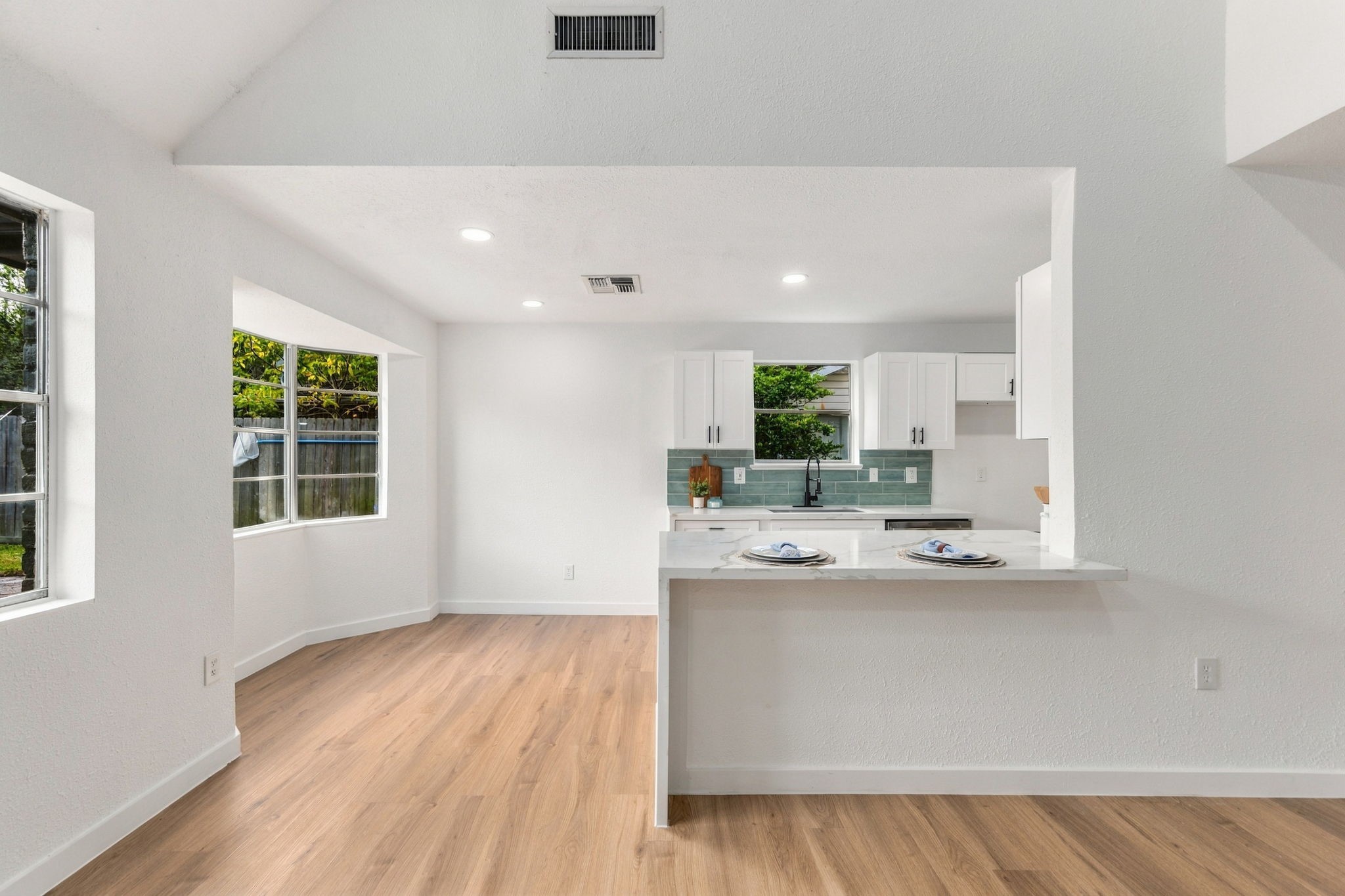 Custom white cabinetry offers a clean, timeless look with ample storage, while the spacious breakfast bar offers the perfect spot for casual dining or entertaining.