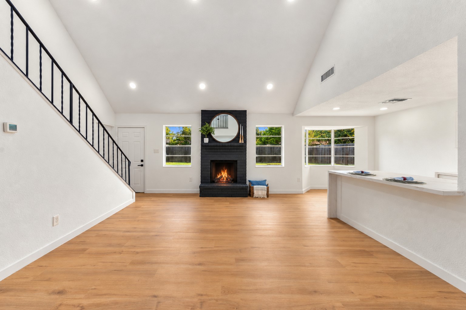 Spacious, open-concept living with luxury vinyl plank flooring, new baseboards, and a striking painted brick fireplace.