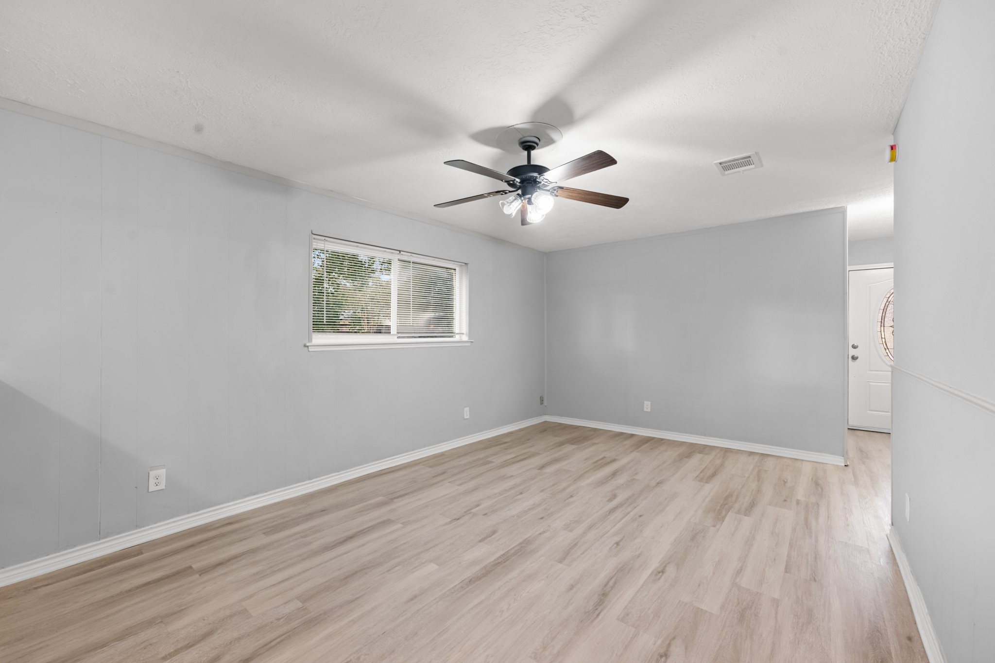 Another perspective showcases the living room's comfortable proportions, natural light, and convenient access to the home's front entry.