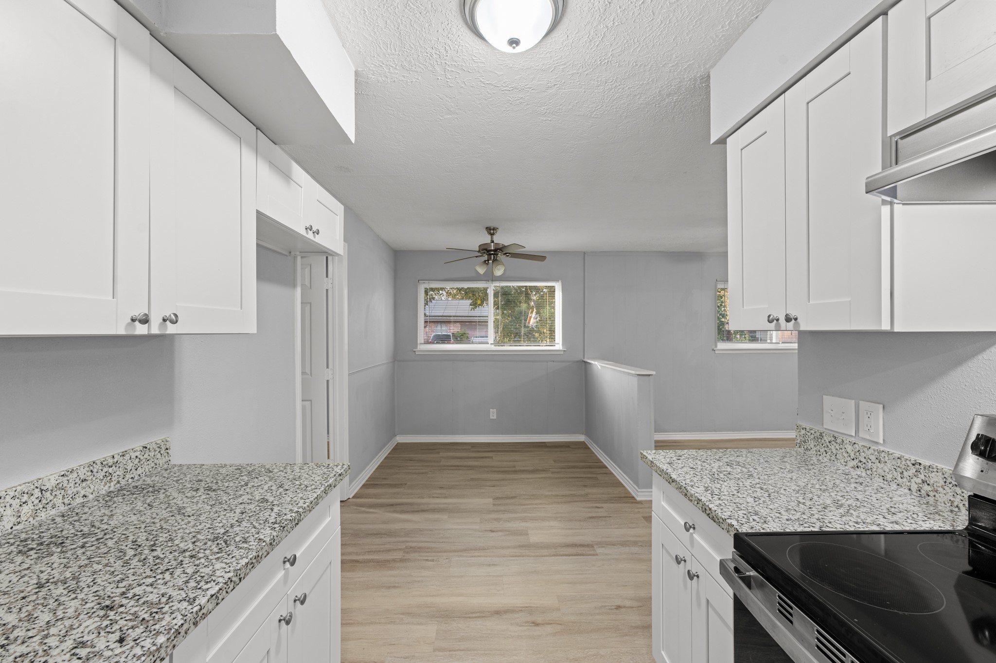 Enjoy the easy flow between the updated kitchen and adjoining dining area, featuring wood-look flooring, abundant natural light, and a ceiling fan for added comfort.