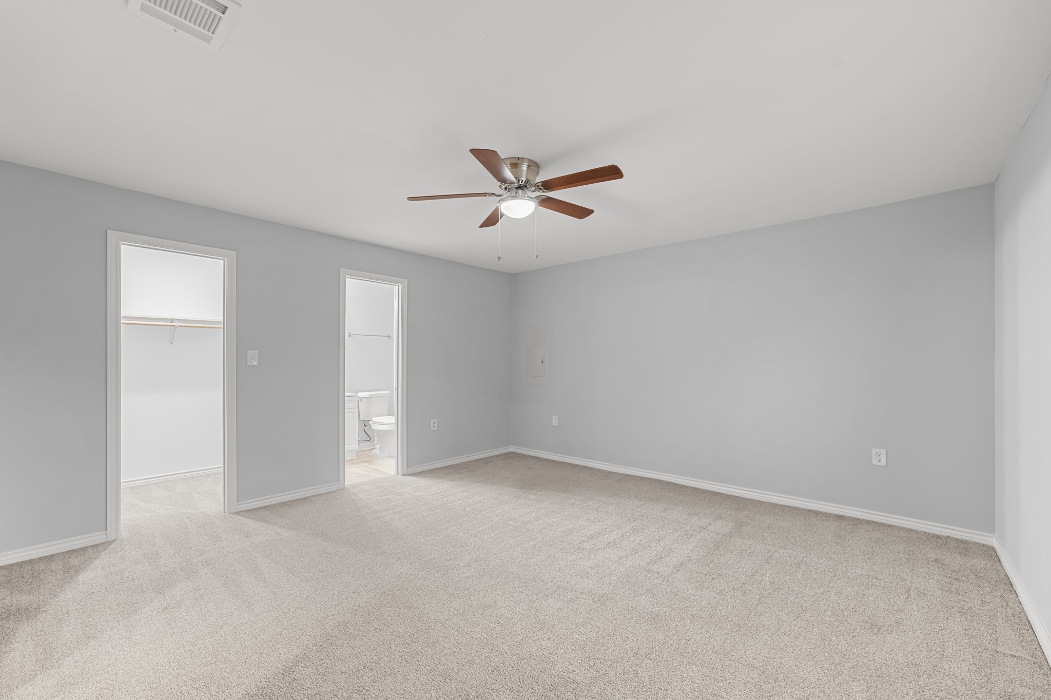 This additional view showcases the primary suite's walk-in closet, direct bathroom access, and ample wall space for arranging furniture to suit your needs.