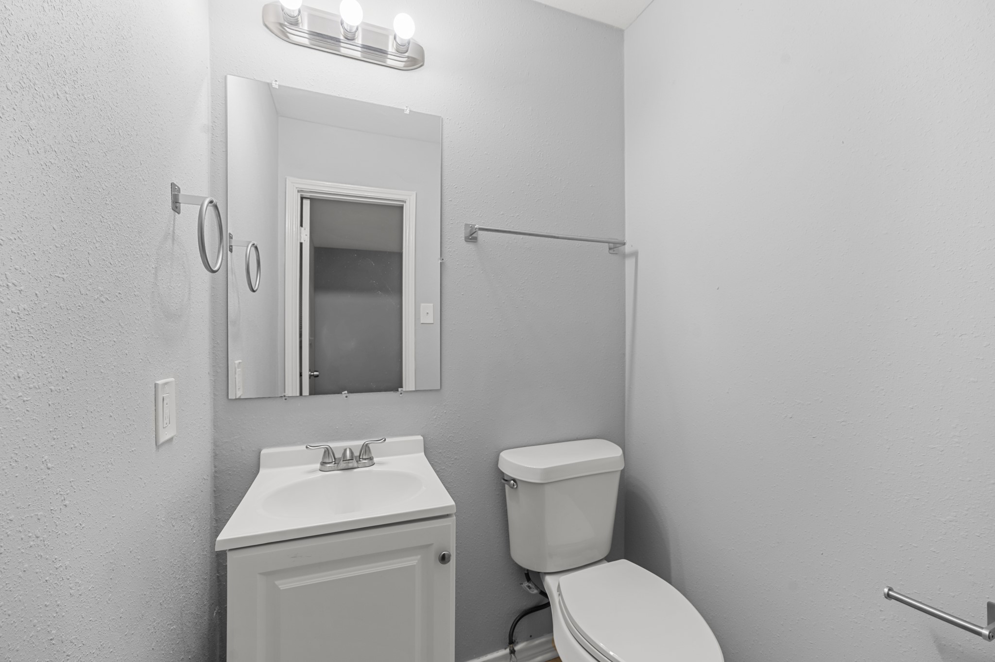 Convenient half bath featuring a white vanity, coordinating fixtures, and neutral gray walls, providing an additional bathroom for guests and everyday use.