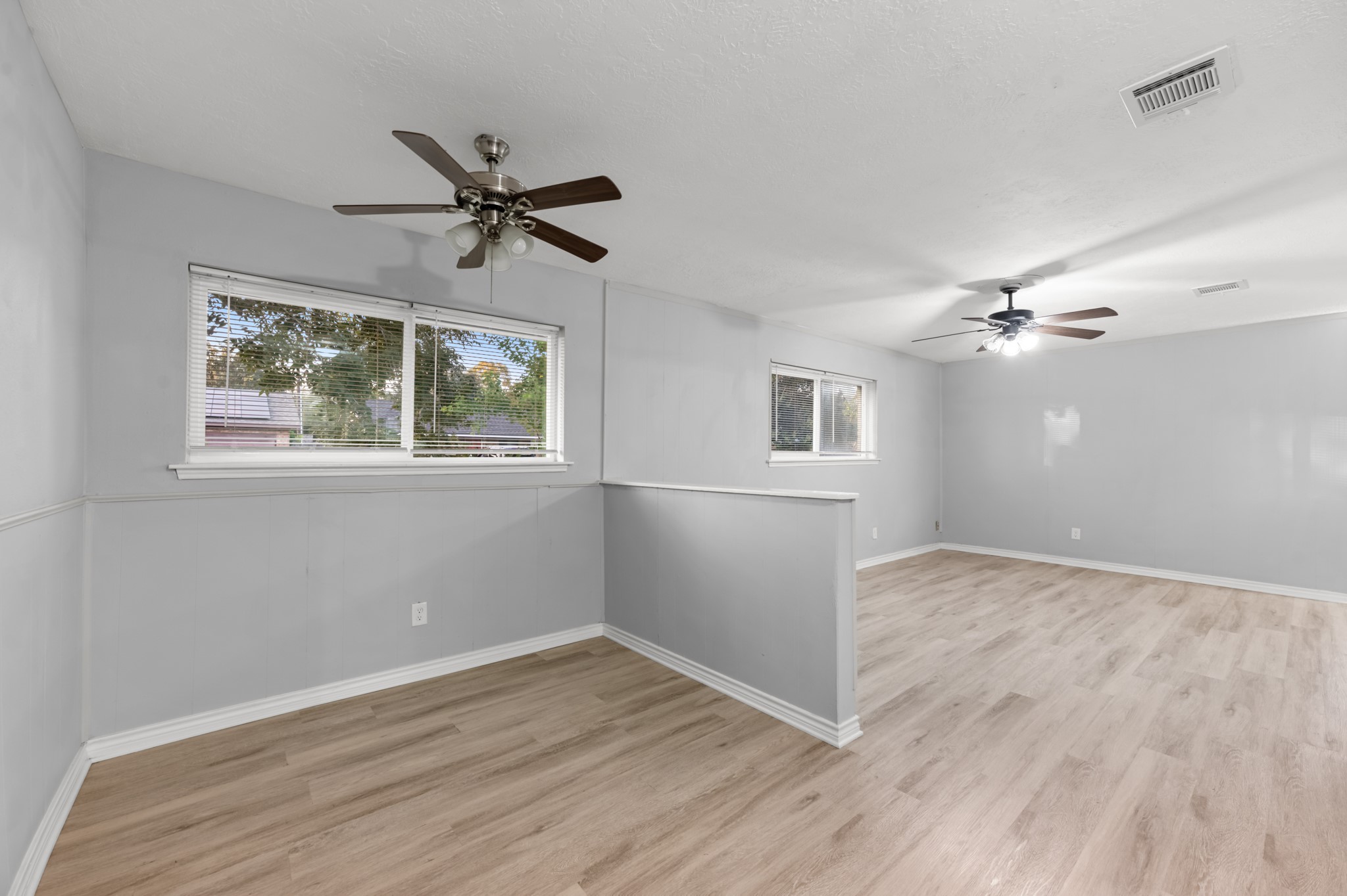 The adjoining living and dining spaces are thoughtfully defined by a partial-height wall while maintaining an open feel, with windows bringing natural light into both areas.