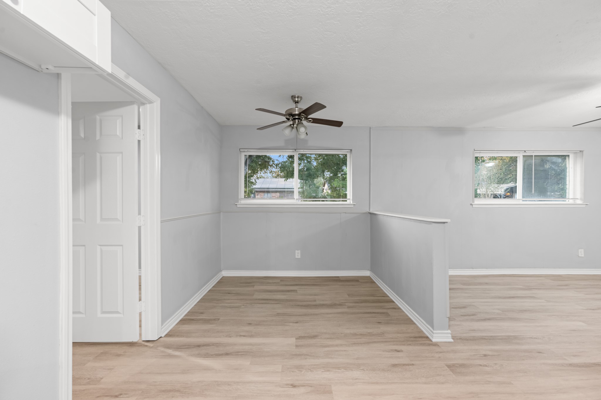 The dedicated dining area features classic wainscoting, a ceiling fan, and a large window, offering a welcoming space for everyday meals and gatherings.