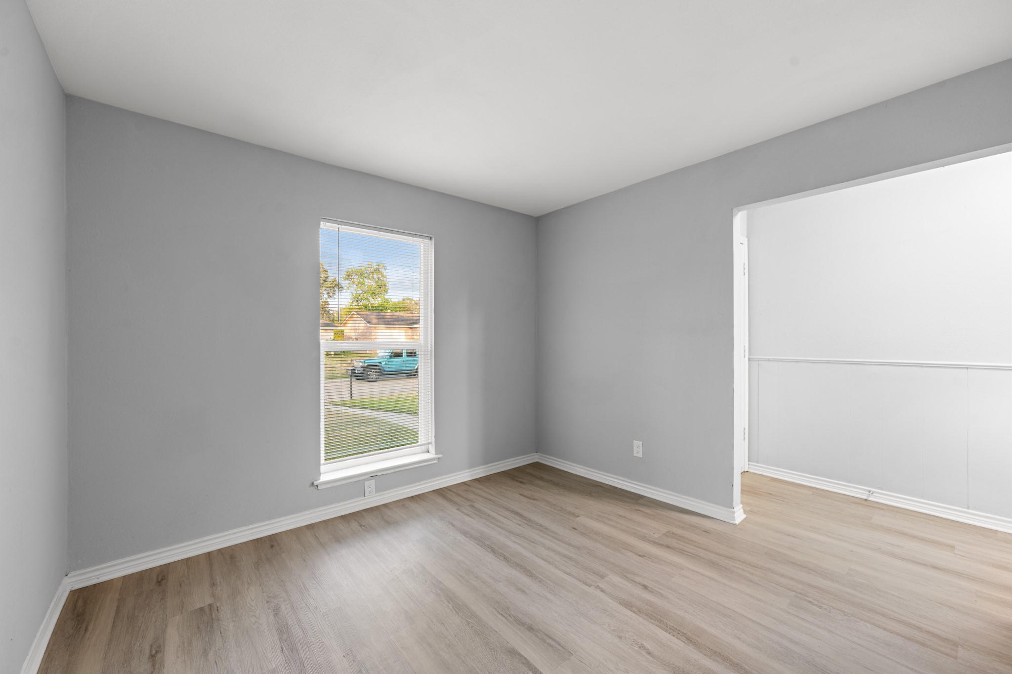 Another view of the home office highlights its generous wall space, natural light, and convenient connection to the adjoining entry area.