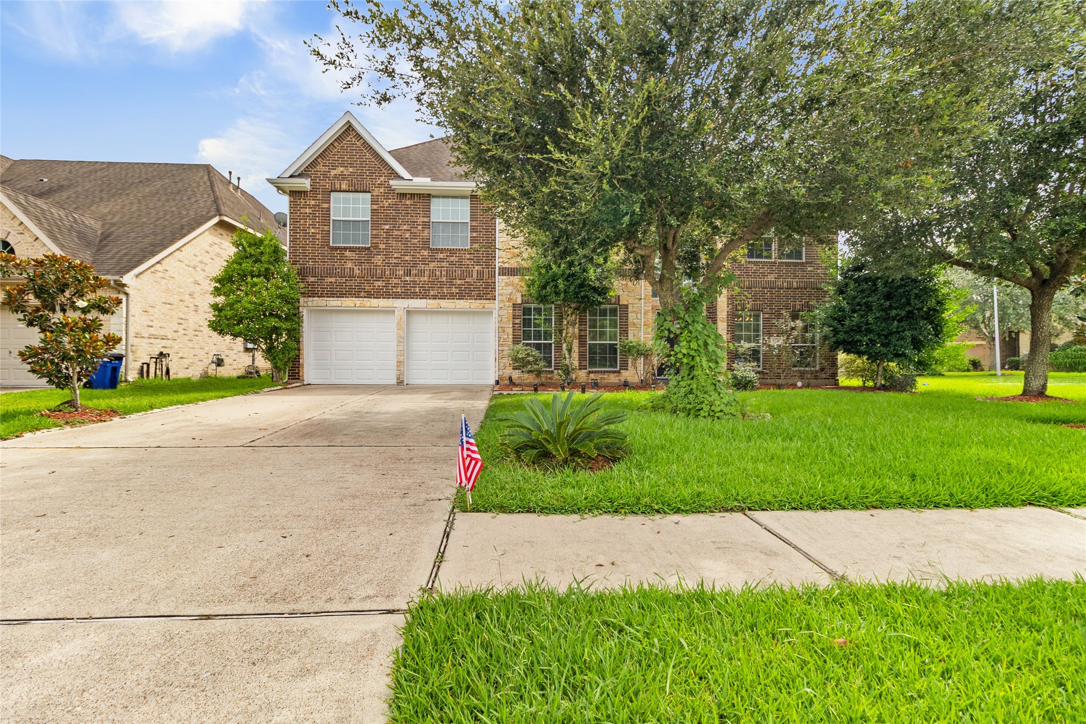 Coming home feels inviting with mature shade trees, a wide driveway, and timeless brick-and-stone curb appeal.