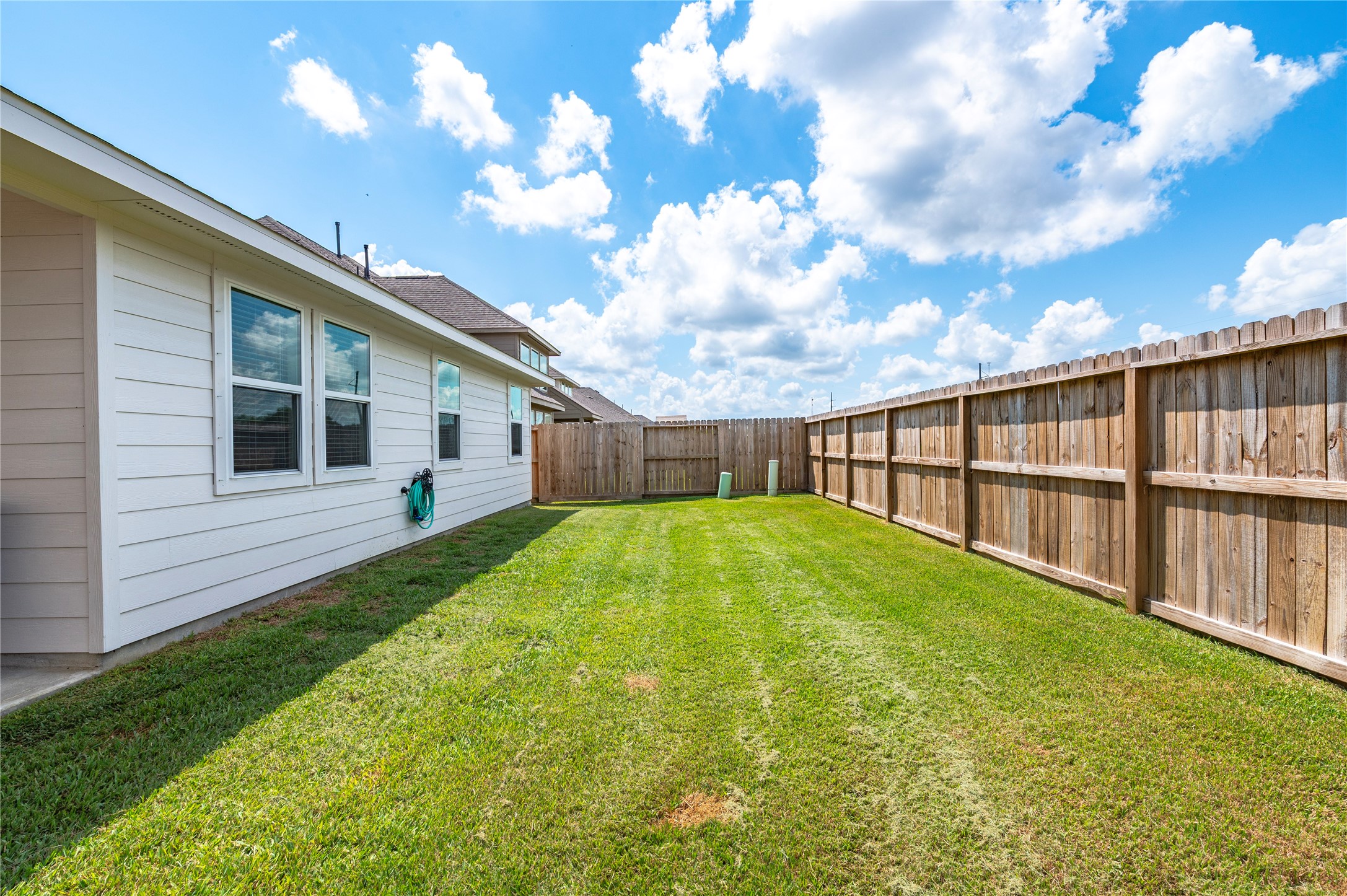 Spacious backyard with a well-maintained lawn, bordered by a new wooden privacy fence, perfect for outdoor activities and relaxation.