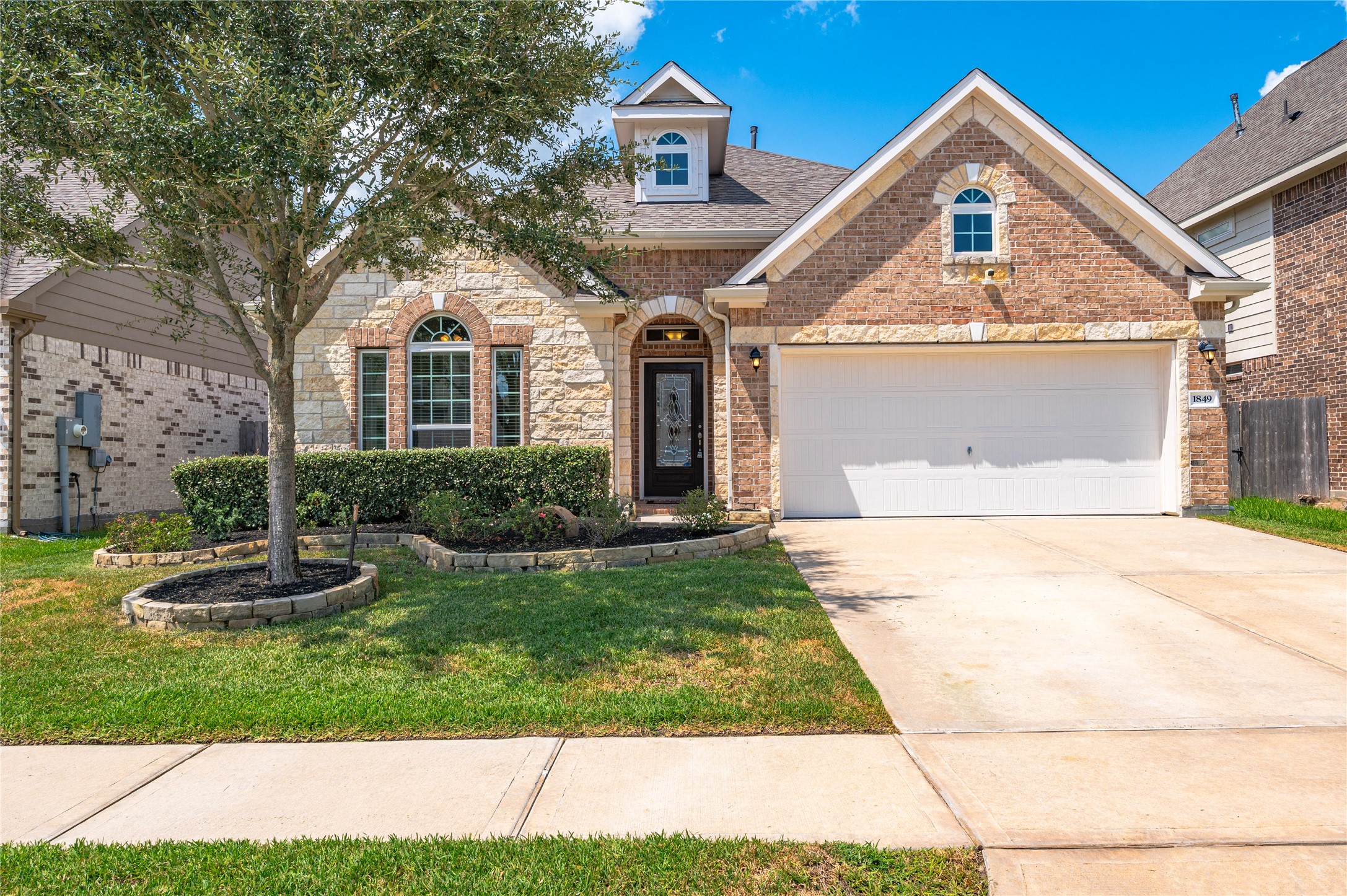 Appealing brick home with a beautifully landscaped front yard, featuring a two-car garage and a welcoming arched entryway. Appealing brick home with a beautifully landscaped front yard, featuring a two-car garage and a welcoming arched entryway.