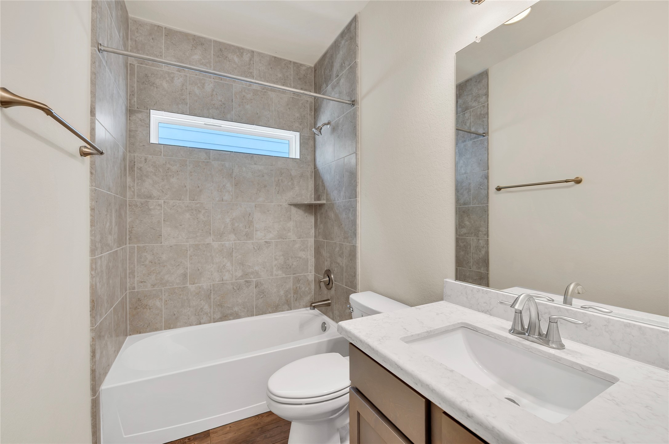 Modern bathroom featuring a sleek vanity with a quartz countertop, a bathtub with elegant tile surround, and a large mirror enhancing the space.