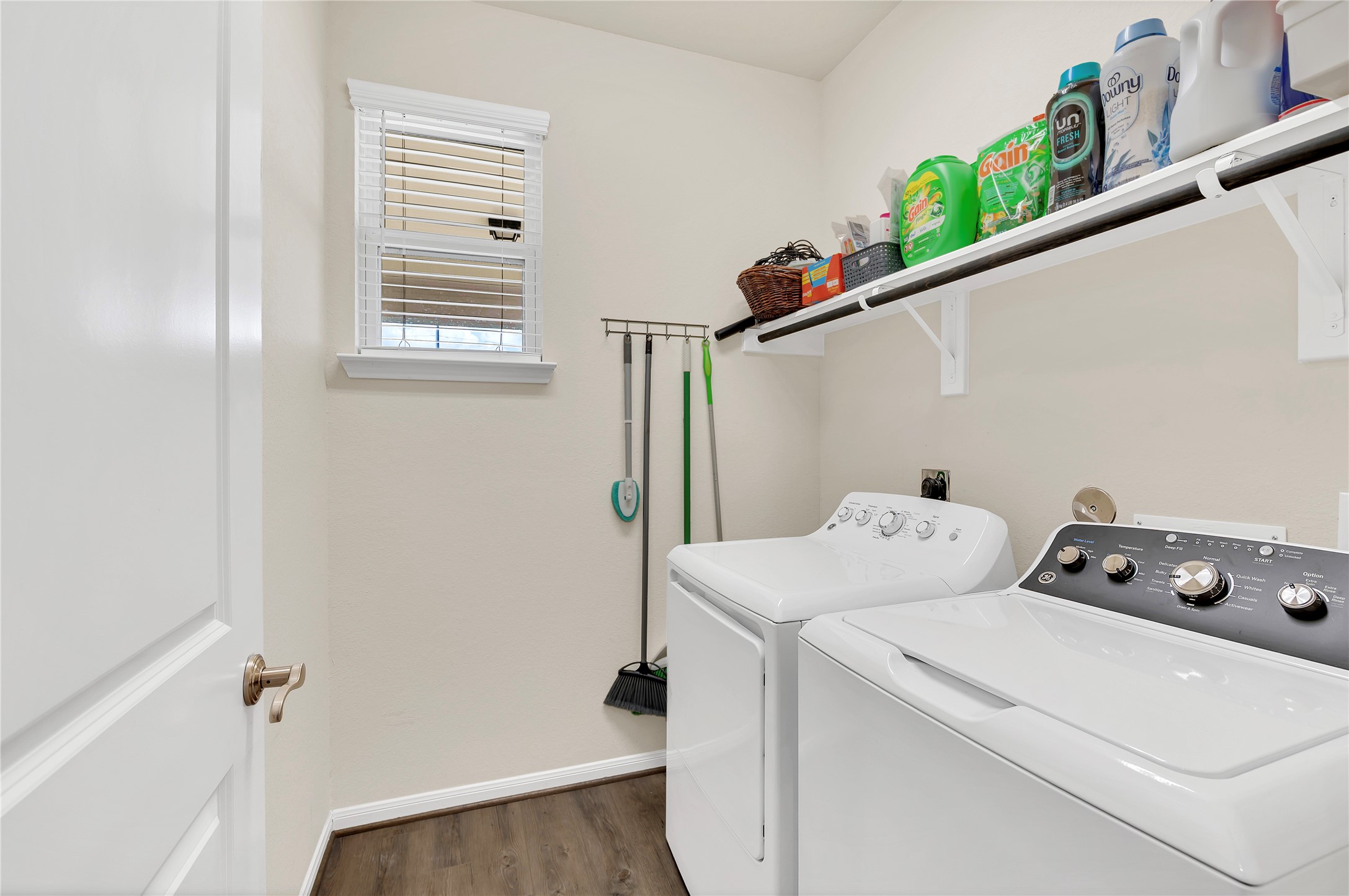 Bright and functional laundry room with ample shelving for storage, and a convenient hanging rack for cleaning essentials.