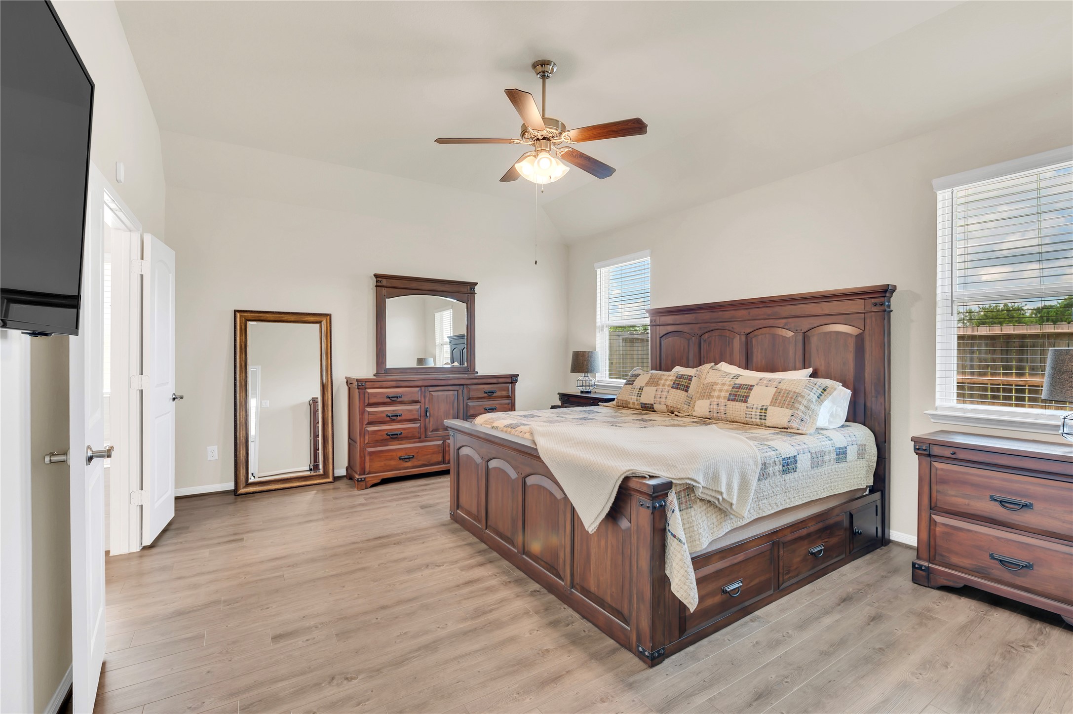 Spacious bedroom featuring elegant upgraded flooring, a ceiling fan, and ample natural light.