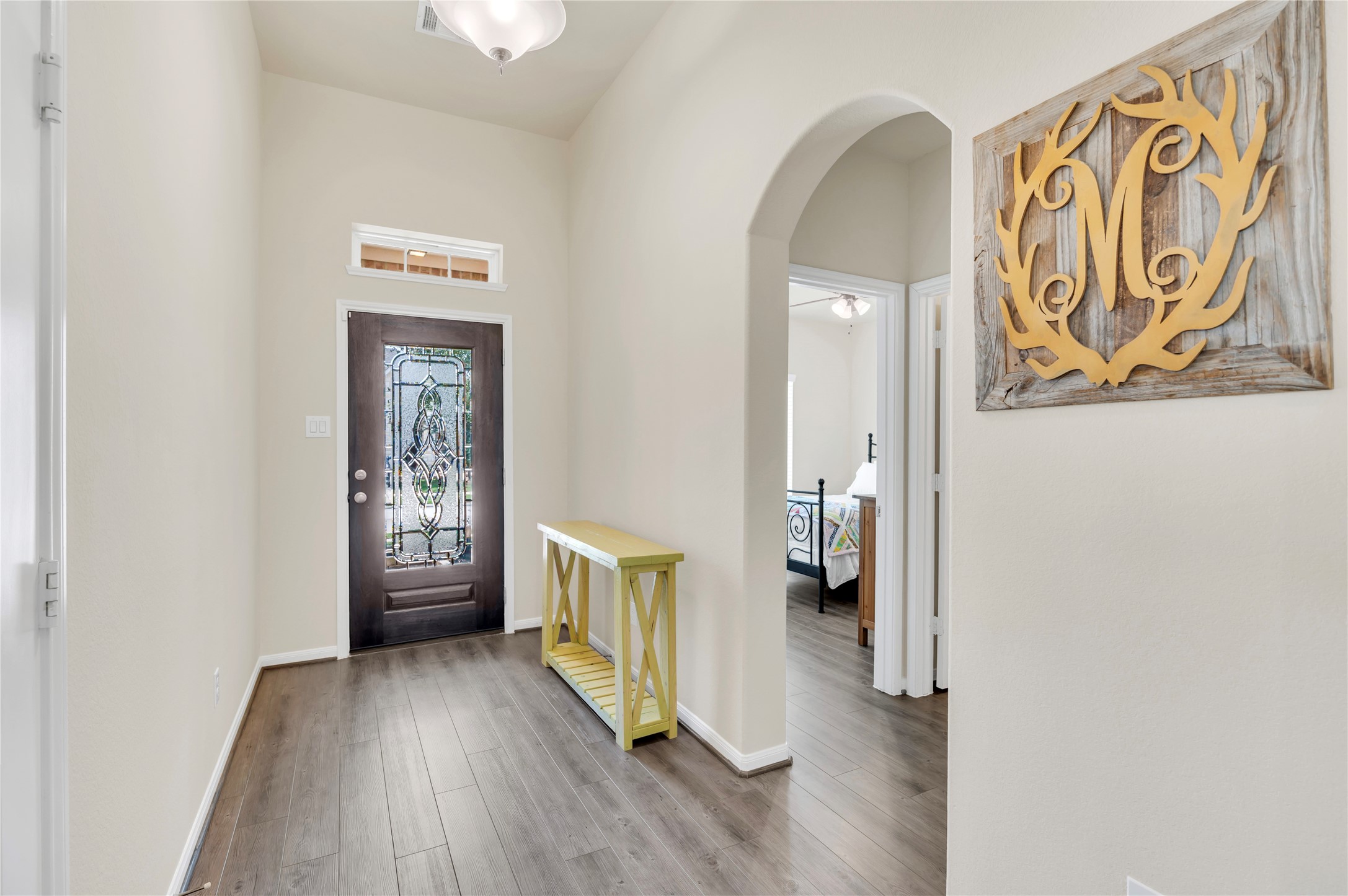 Inviting entryway with elegant dark wood flooring, a decorative glass front door, and a charming archway leading to the living spaces. Inviting entryway with elegant dark wood flooring, a decorative glass front door, and a charming archway leading to the living spaces.