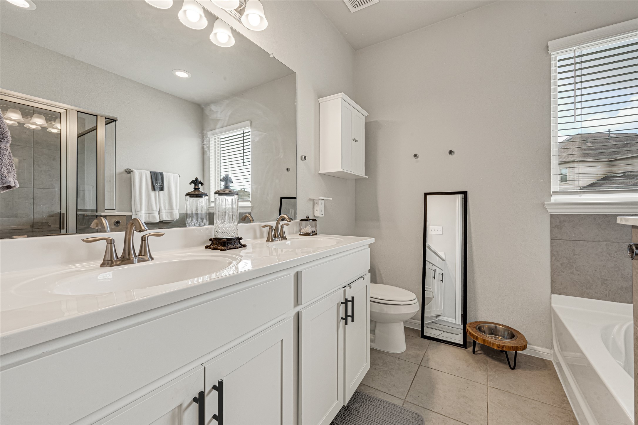 Primary bathroom featuring dual vanities.