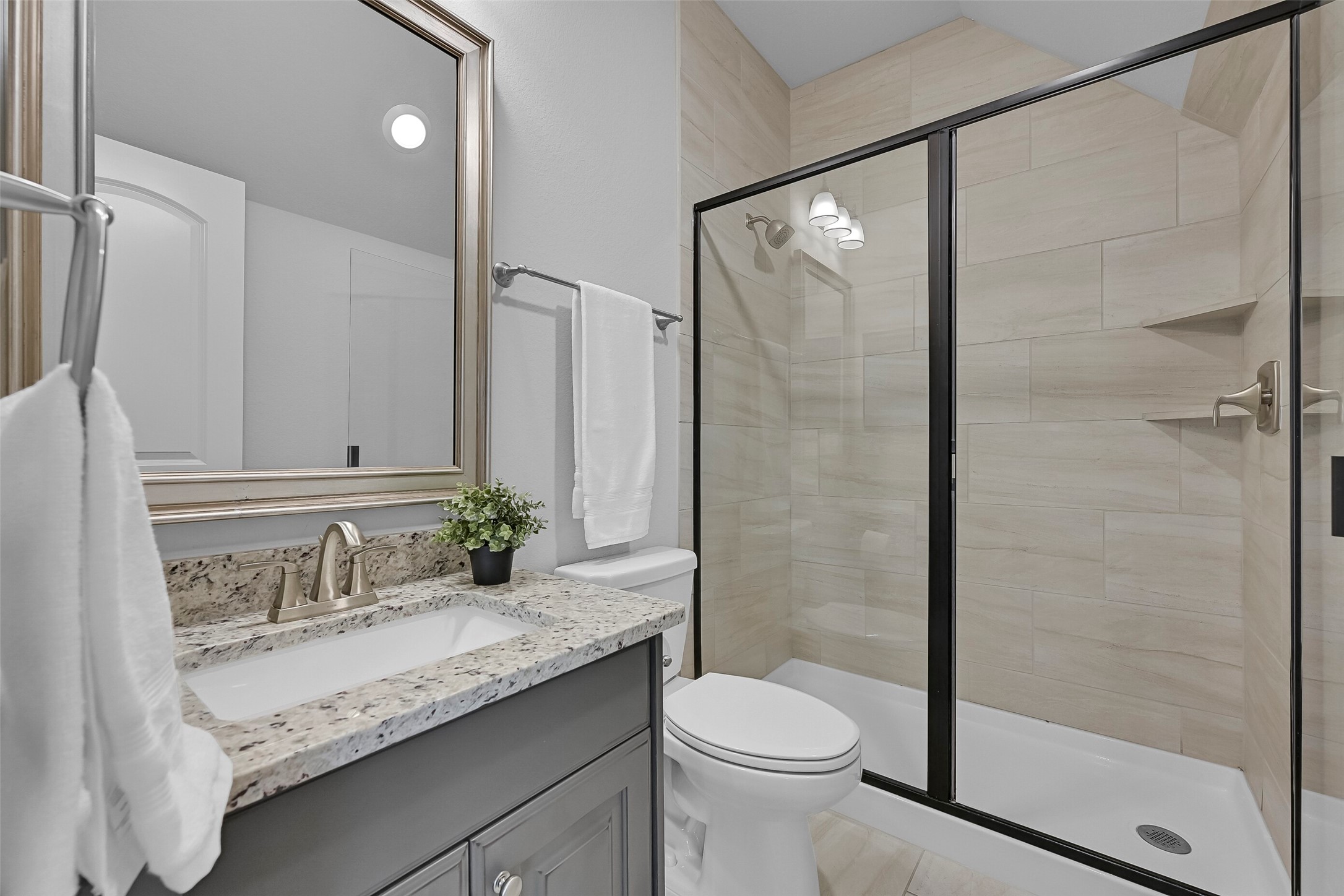 Serving the upstairs gameroom and media room, this full bathroom features granite countertops, upgraded cabinetry, and a spacious tiled walk-in shower with glass enclosure and built-in shelving. Having a full bath on the second floor adds convenience for guests and makes this level a truly functional extension of the home.