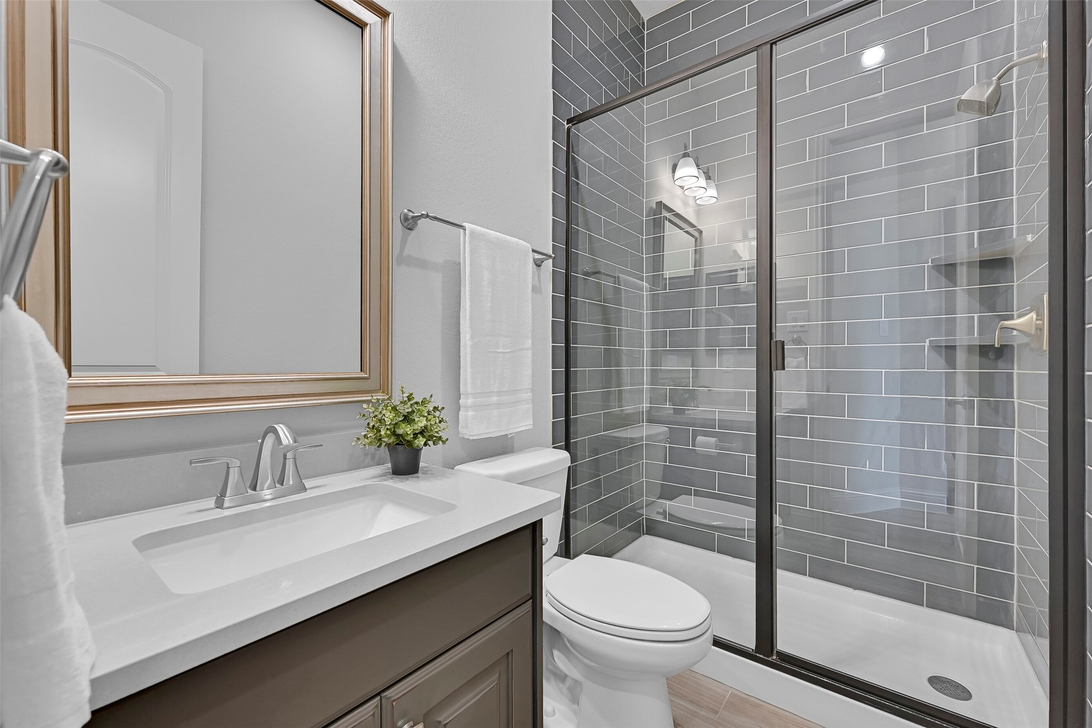 Conveniently located just outside the bedroom and near the front foyer, this full bath features an upgraded vanity with quartz countertop, framed mirror, and a beautifully tiled walk-in shower with sleek glass enclosure. The designer finishes make it perfect for guests while maintaining privacy from the home's main living spaces.