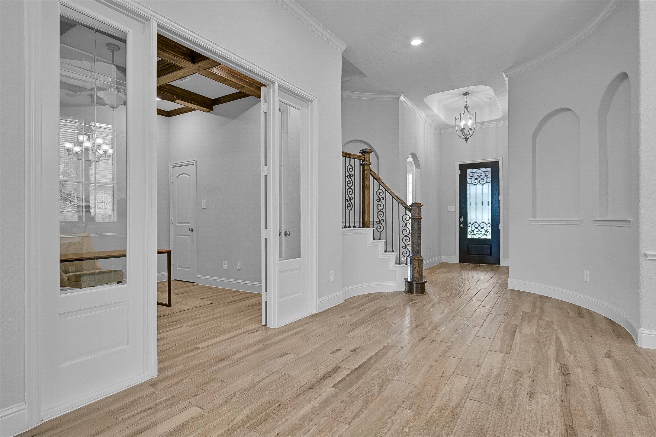 From the foyer, notice the impressive 12-foot tray ceiling accented by a chandelier, curved architectural walls, recessed lighting, and elegant trim work. French doors lead to the private study while the staircase creates a beautiful focal point for the entry.