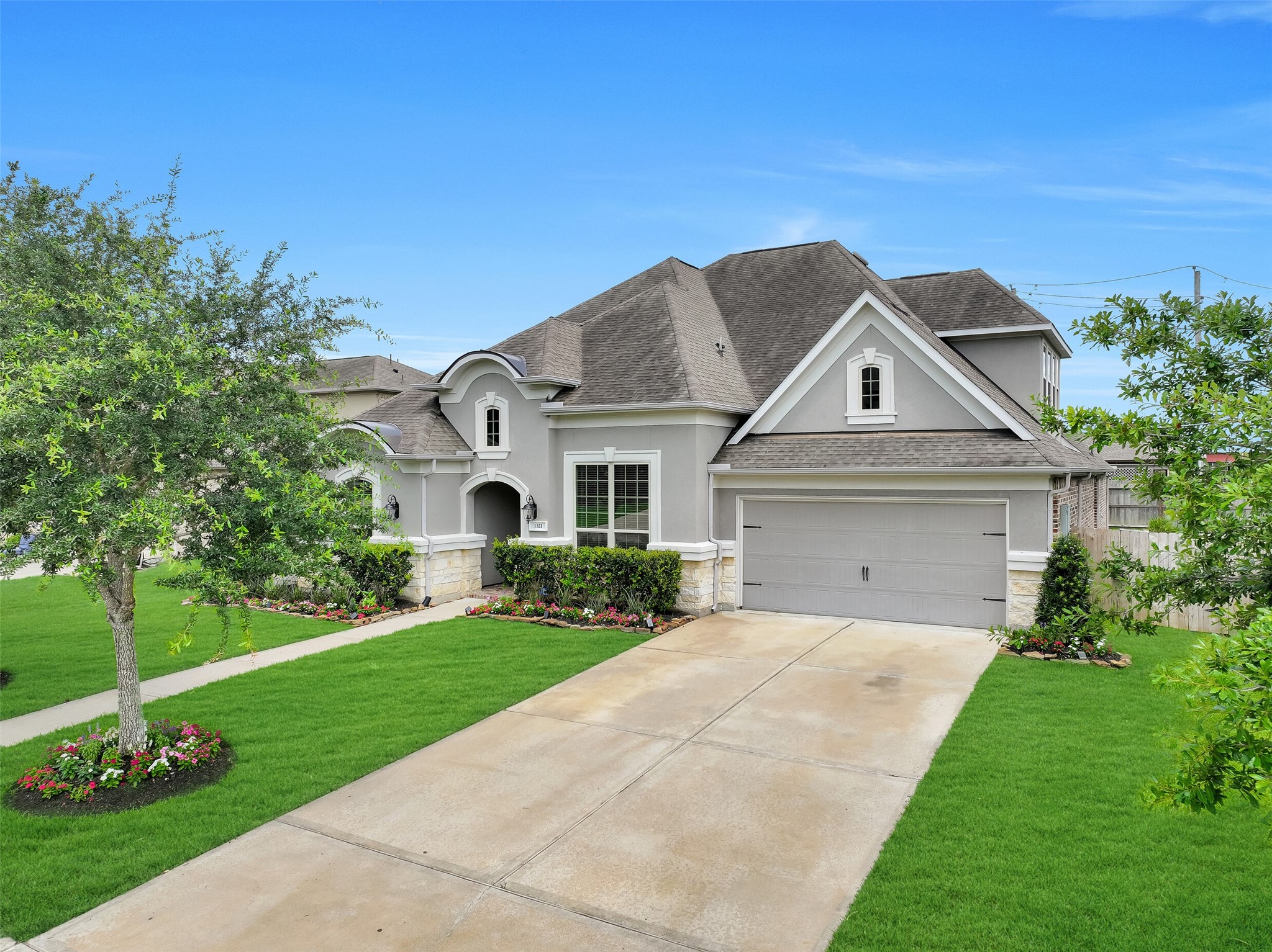 From this angle, the home's impressive curb appeal comes into full view with its stucco and stone exterior, mature oak trees, fresh landscaping, solar-powered landscape lighting, and double-wide driveway leading to the tandem 3-car garage. Located within the gated Arbor Gate section of West Ranch and zoned to Friendswood ISD.