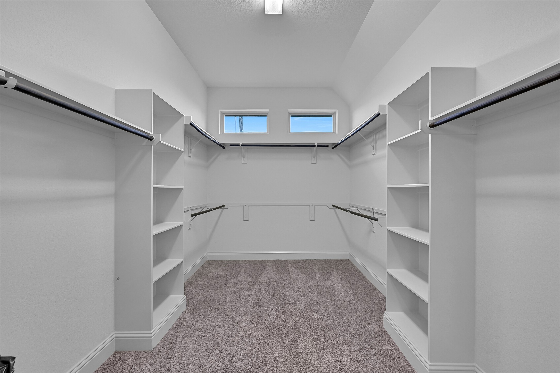 The enormous walk-in closet offers built-in shelving, multiple hanging areas, and abundant storage for every season. High ceilings and transom windows provide natural light, creating an organized and functional extension of the primary suite.