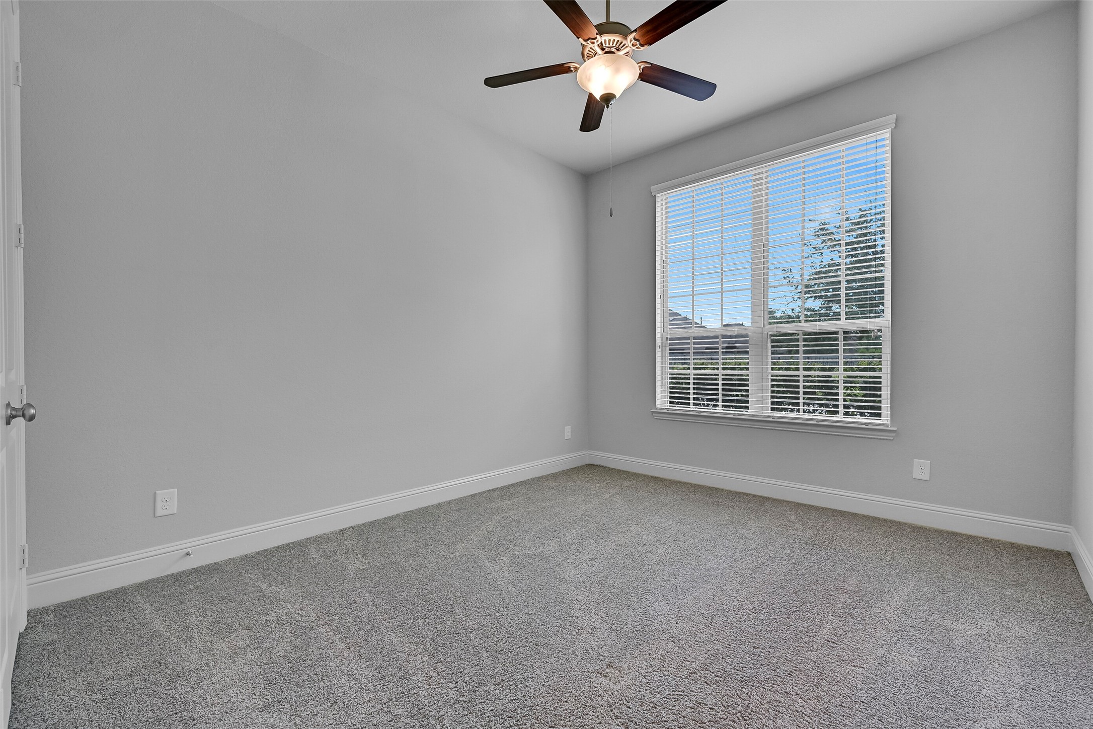 Privately situated near the front of the home, this secondary bedroom offers an ideal setup for guests, extended family, or a home office. Large windows provide natural light, while the neutral color palette, plush carpet, ceiling fan, and generous closet space create a comfortable retreat separated from the main living areas and primary suite.