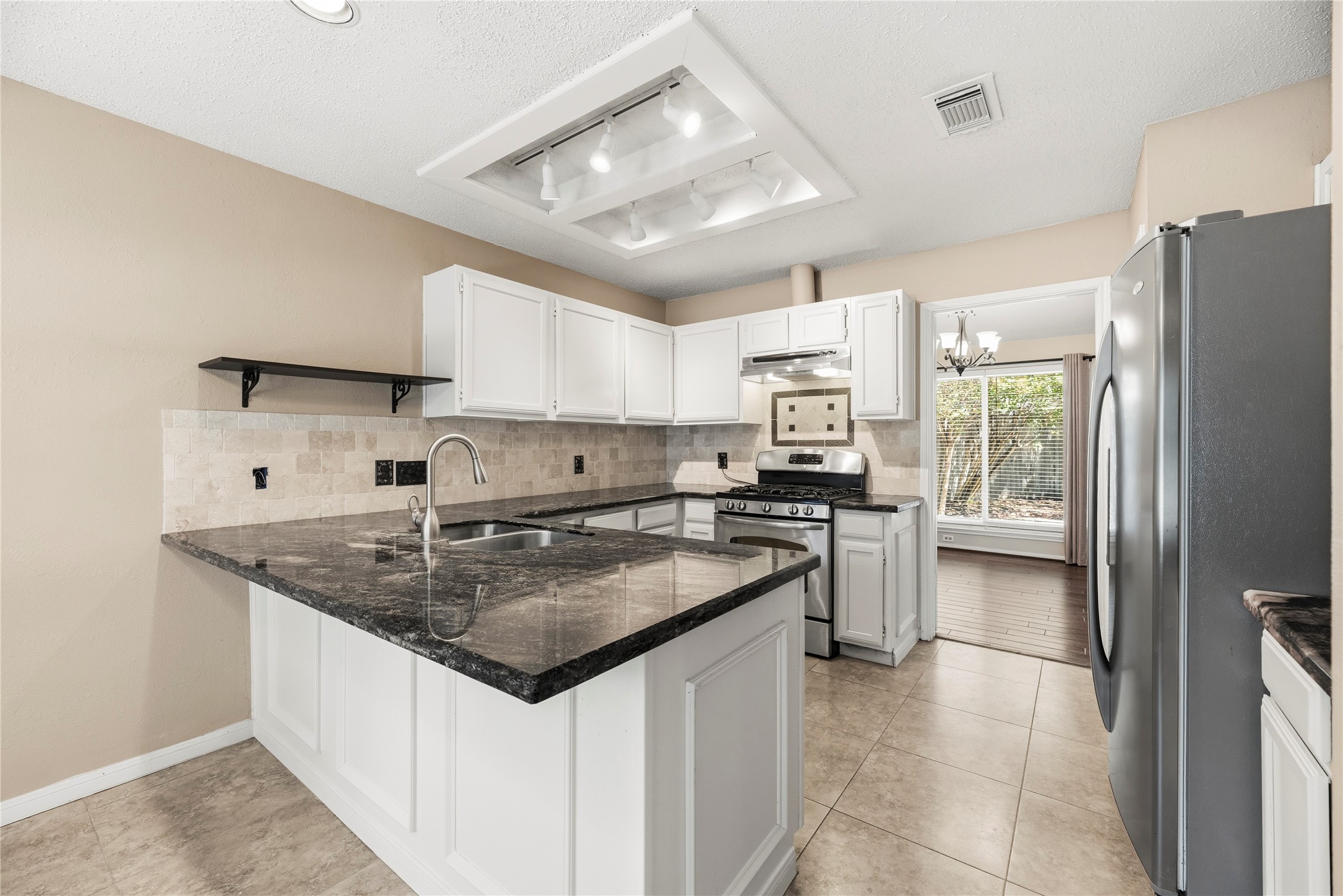 Well appointed kitchen features granite countertops, tile backsplash, stainless steel appliances and a gas range.