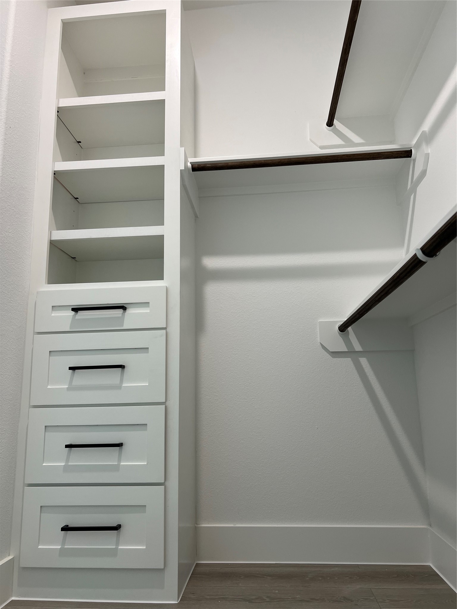 Spacious walk-in primary closet featuring built-in shelving, drawers, and ample hanging space for organized storage.