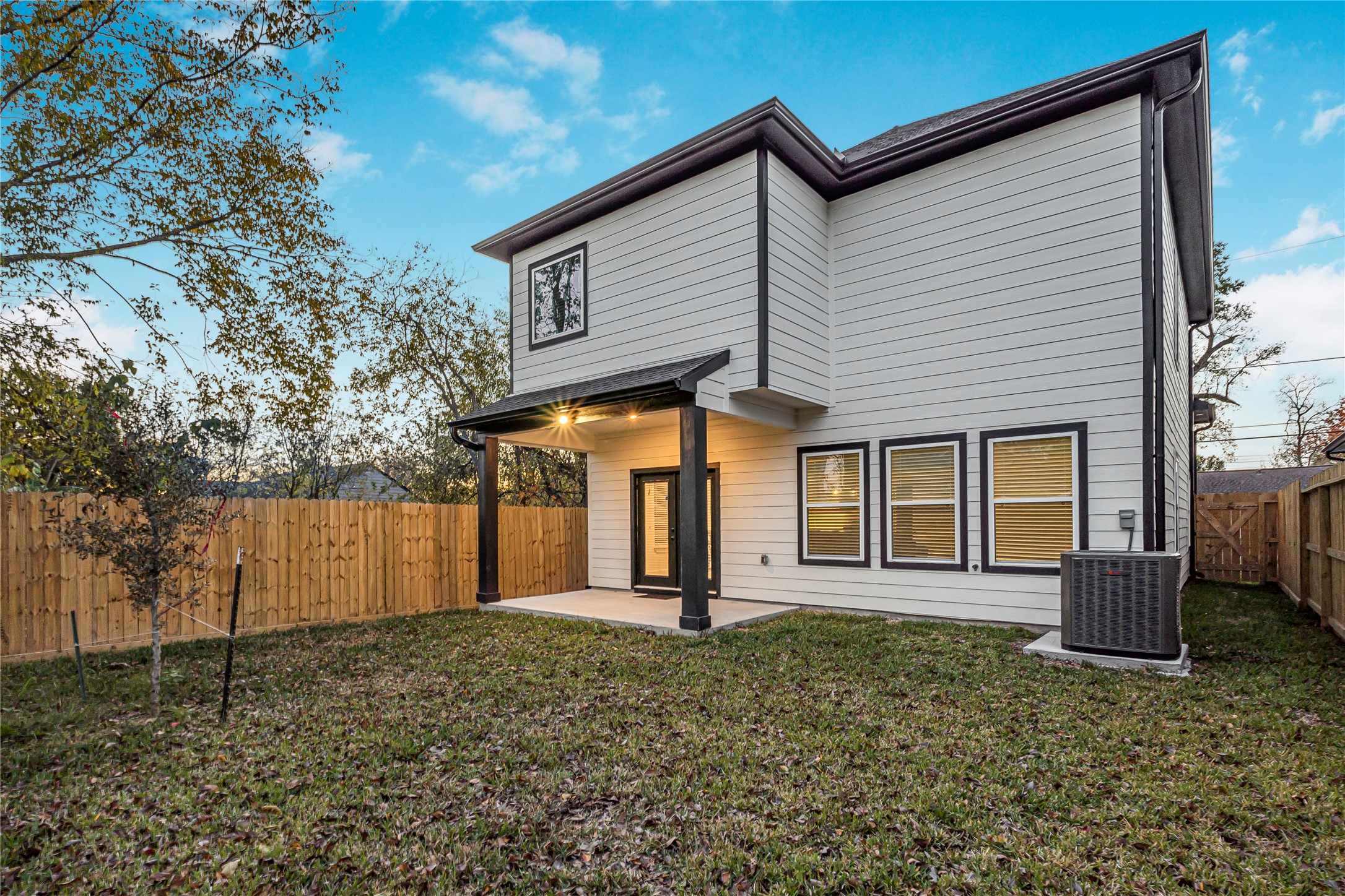 Modern two-story home with a spacious fenced backyard, featuring a covered patio perfect for outdoor relaxation.