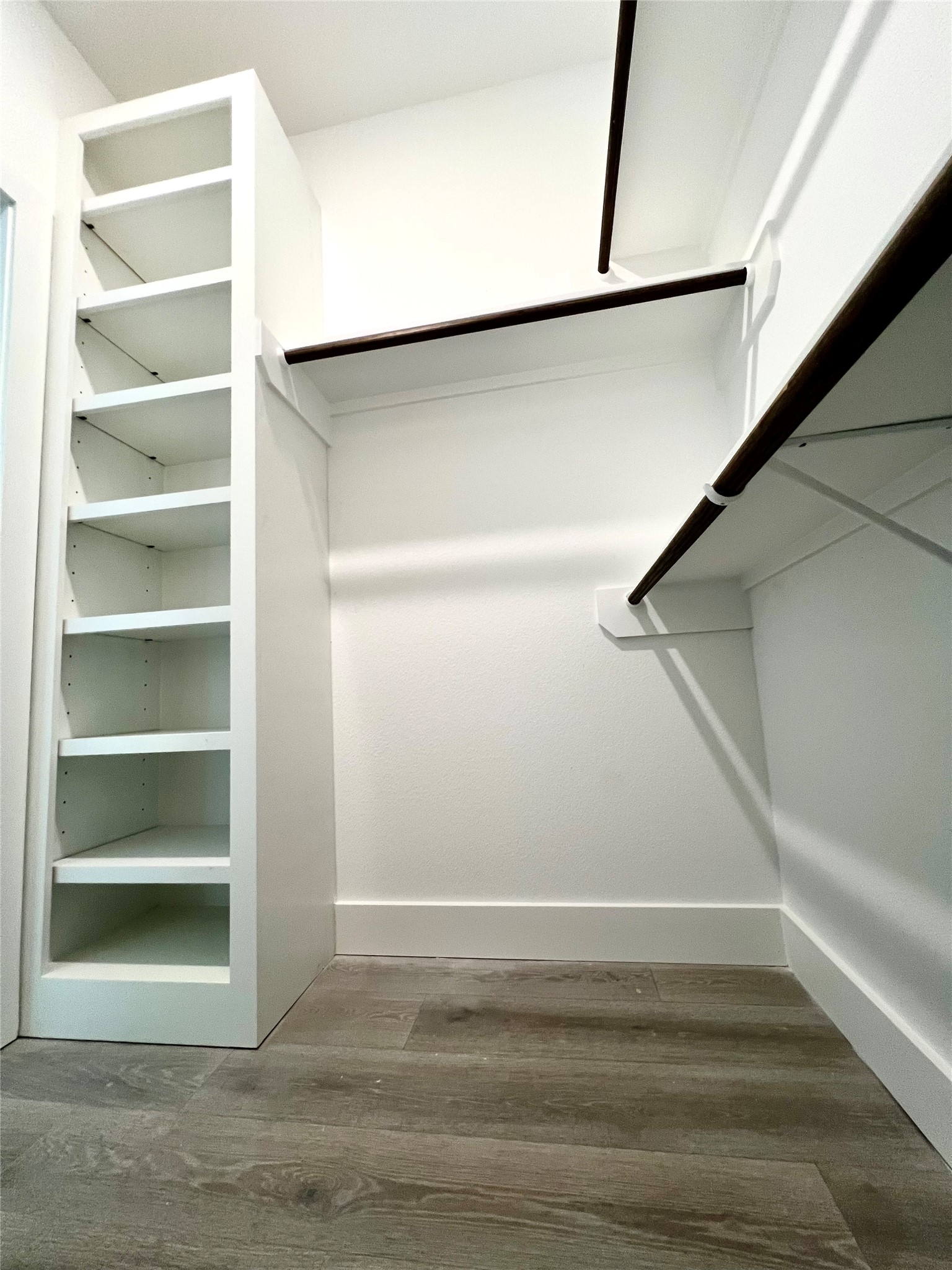 Spacious walk-in primary closet featuring custom shelving and ample hanging space for organized storage.