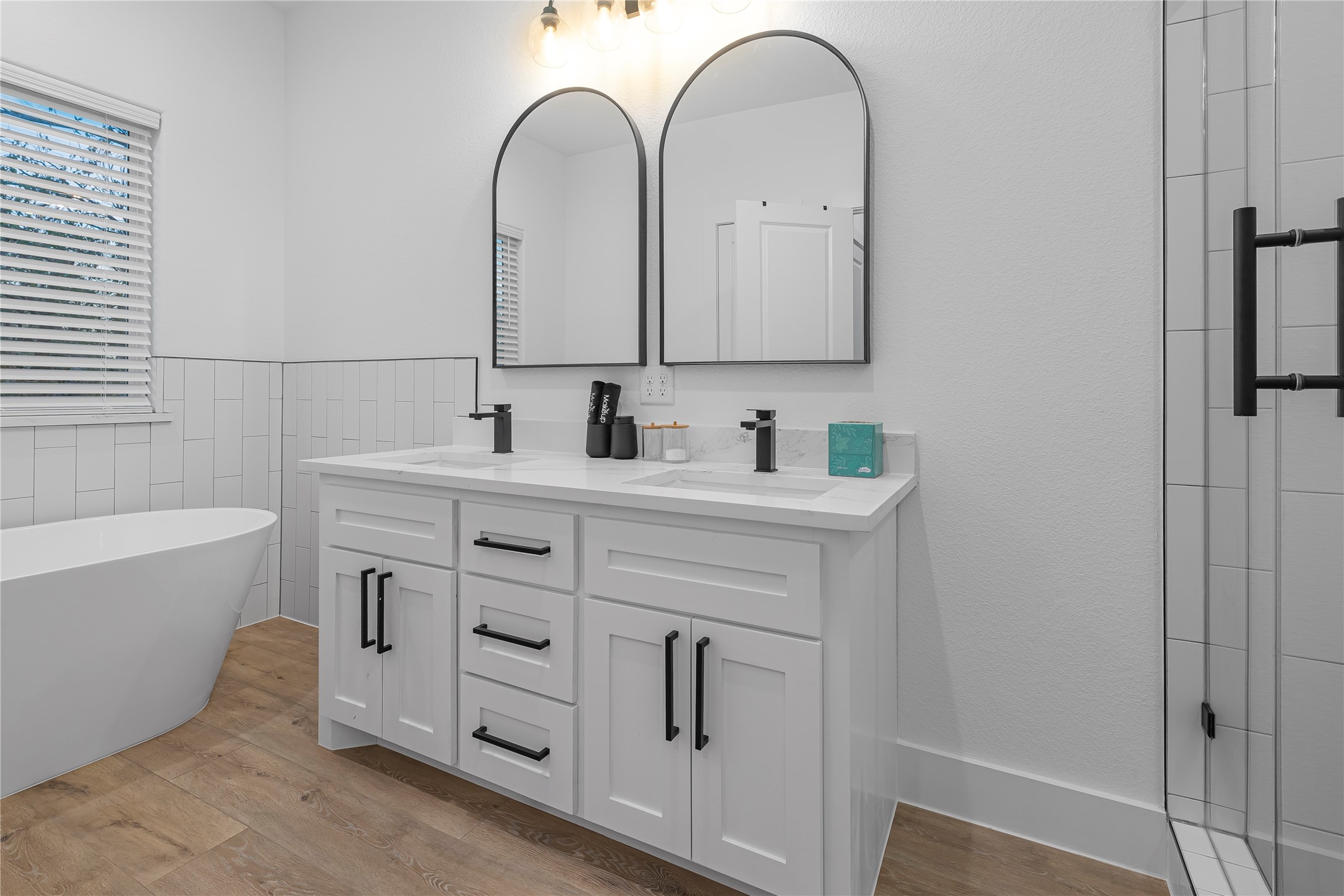 Elegant bathroom with a modern double vanity, stylish black fixtures, and a luxurious freestanding tub.