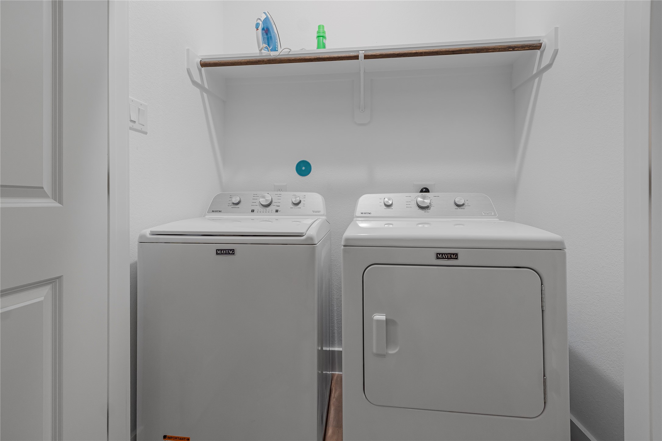 Convenient laundry space featuring a washer and dryer with an overhead shelf for storage.