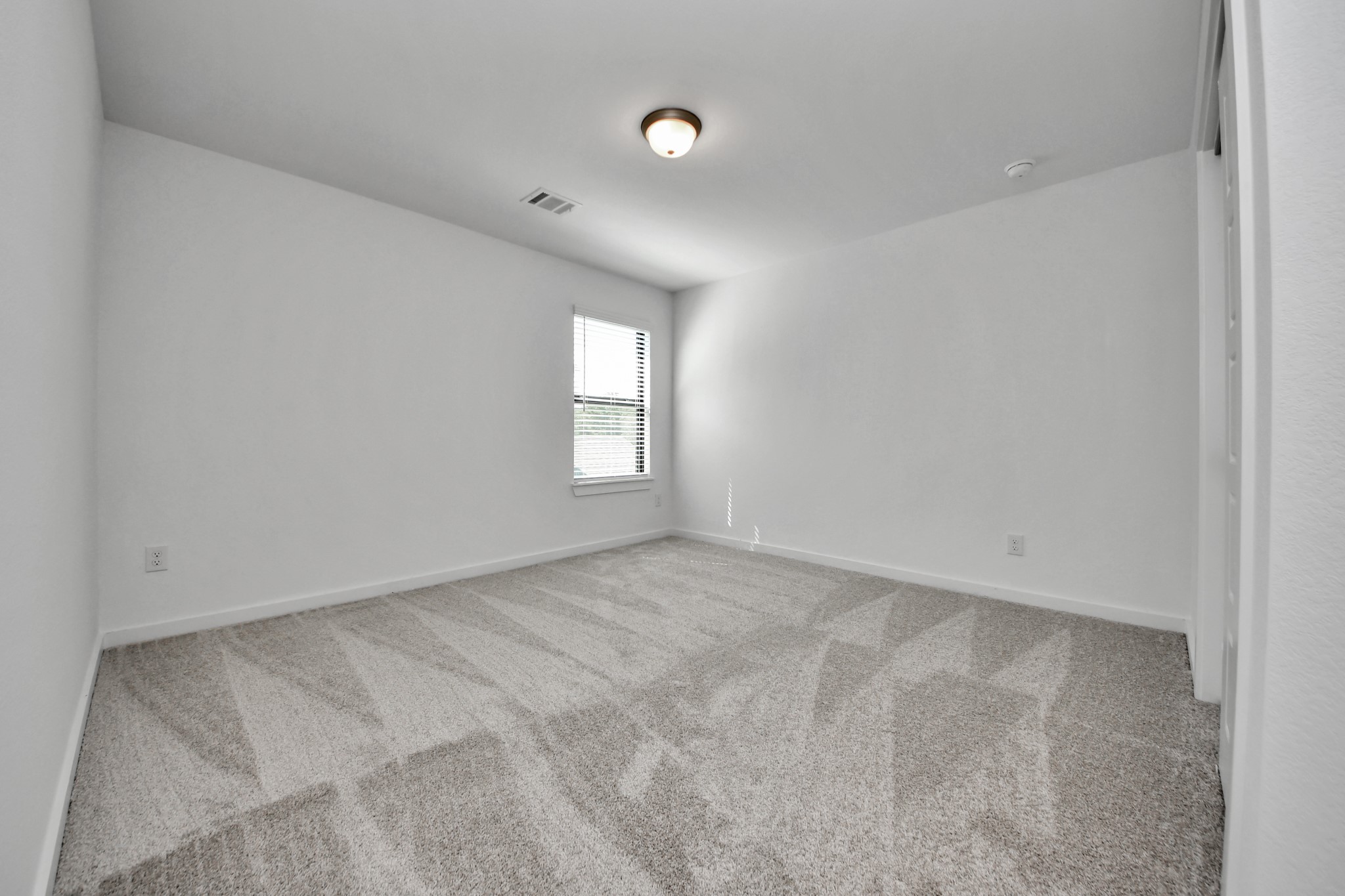 Secondary bedroom features plush carpeting, large windows that let in plenty of natural light, bright paint, and spacious closets.