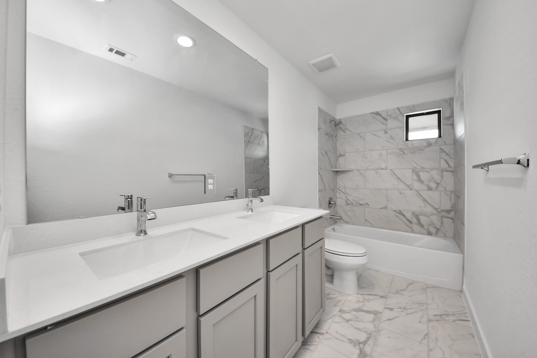 Secondary bath features tile flooring, bath/shower combo with tile surround, light stained wood cabinets, beautiful light countertop.