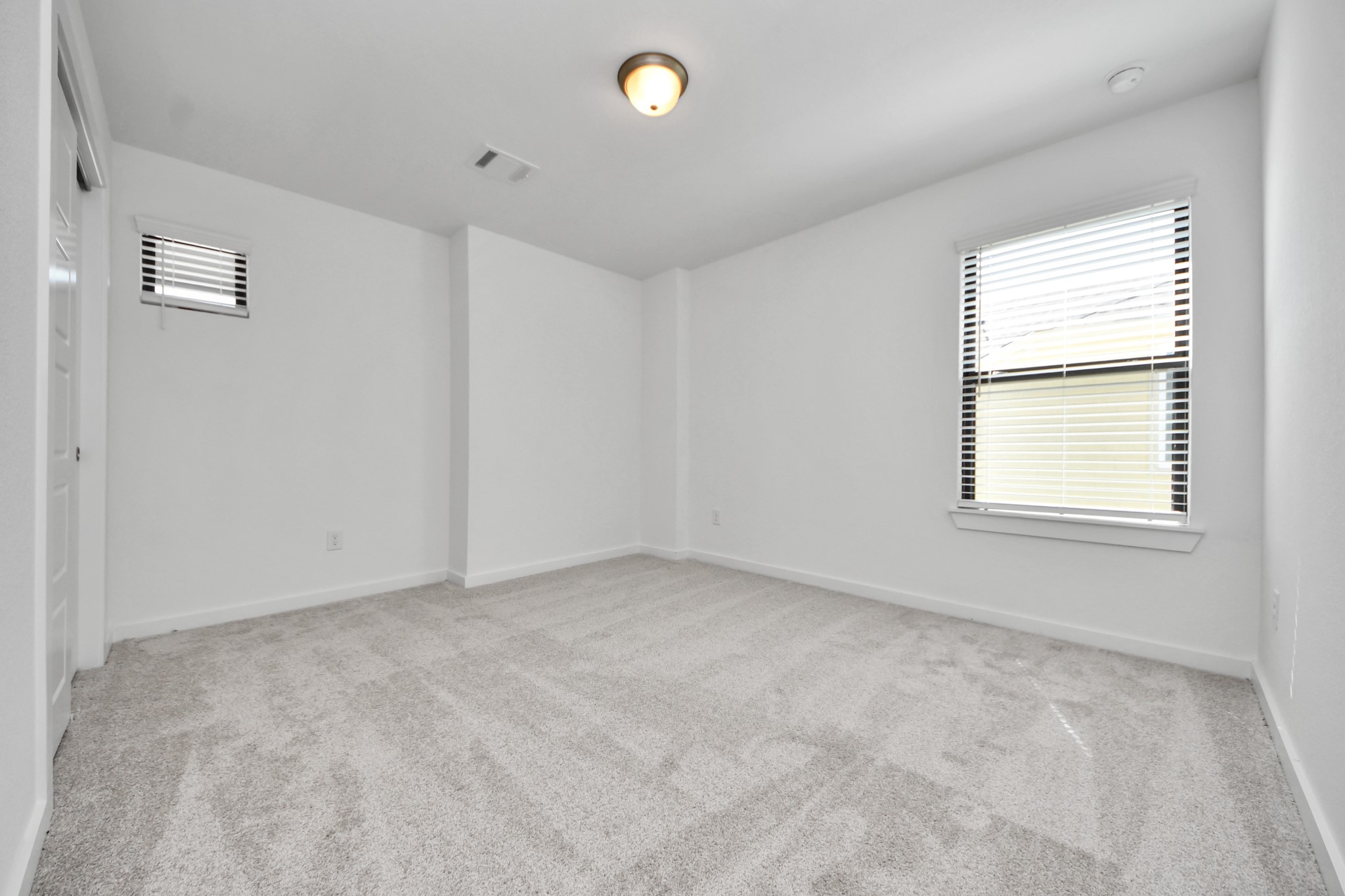 Secondary bedroom features plush carpeting, large windows that let in plenty of natural light, bright paint, and spacious closets.