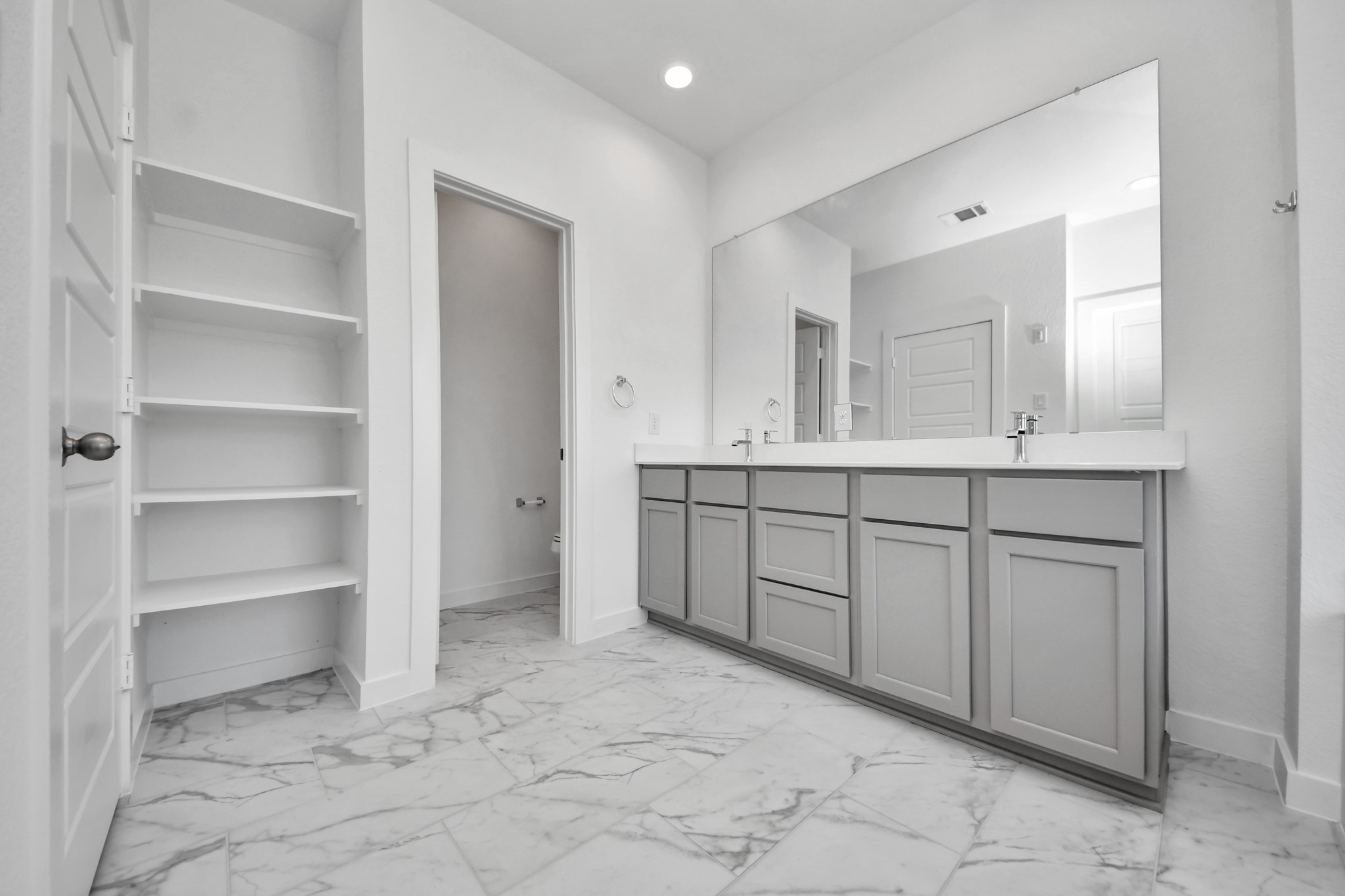 Elevate your daily routine at the elegant vanity, now equipped with double sinks, light countertops, modern hardware, and beautiful recessed lights.