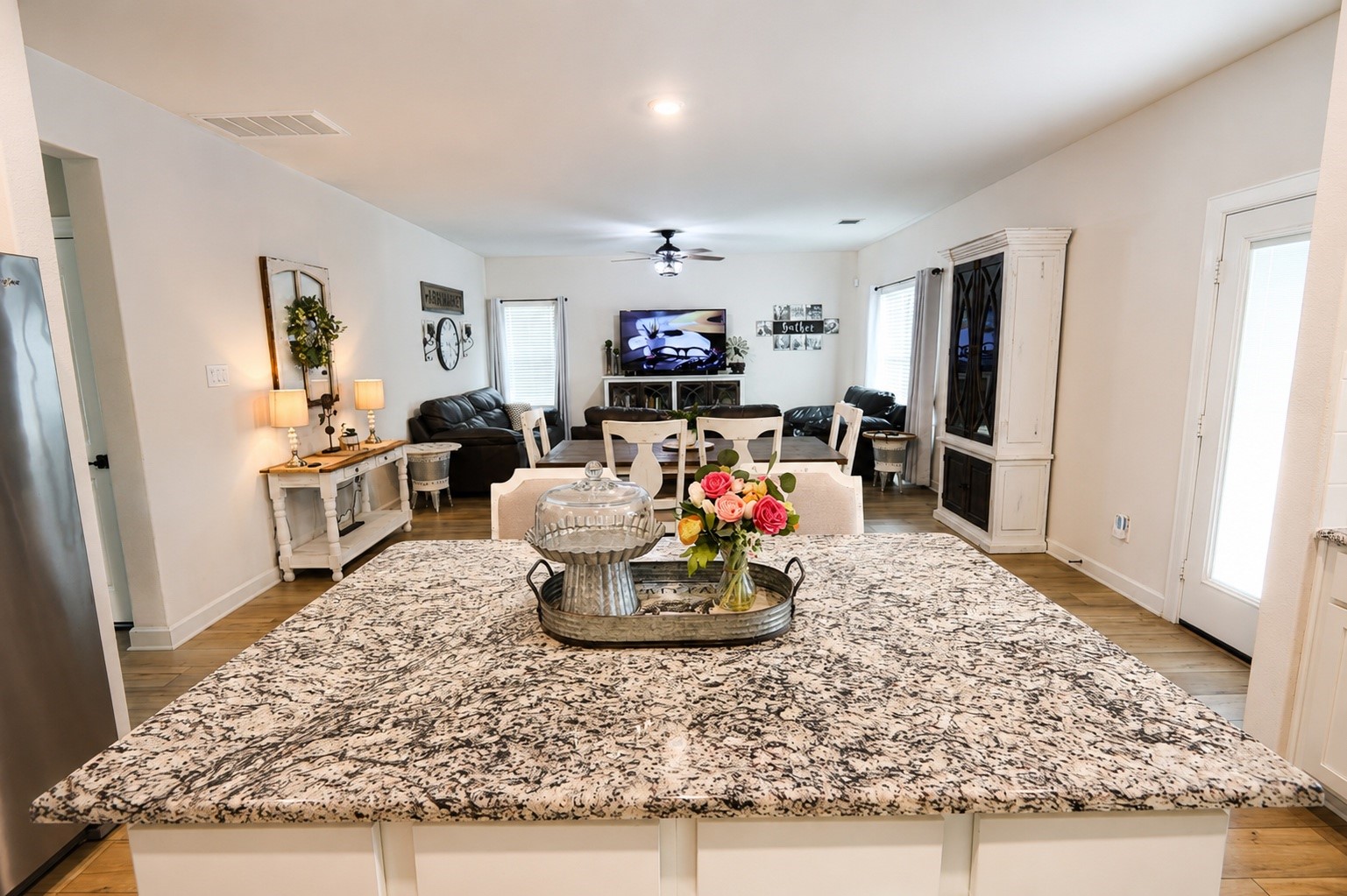 Spacious open-concept living area featuring a stylish granite kitchen island, cozy seating, and abundant natural light, perfect for entertaining and relaxation.