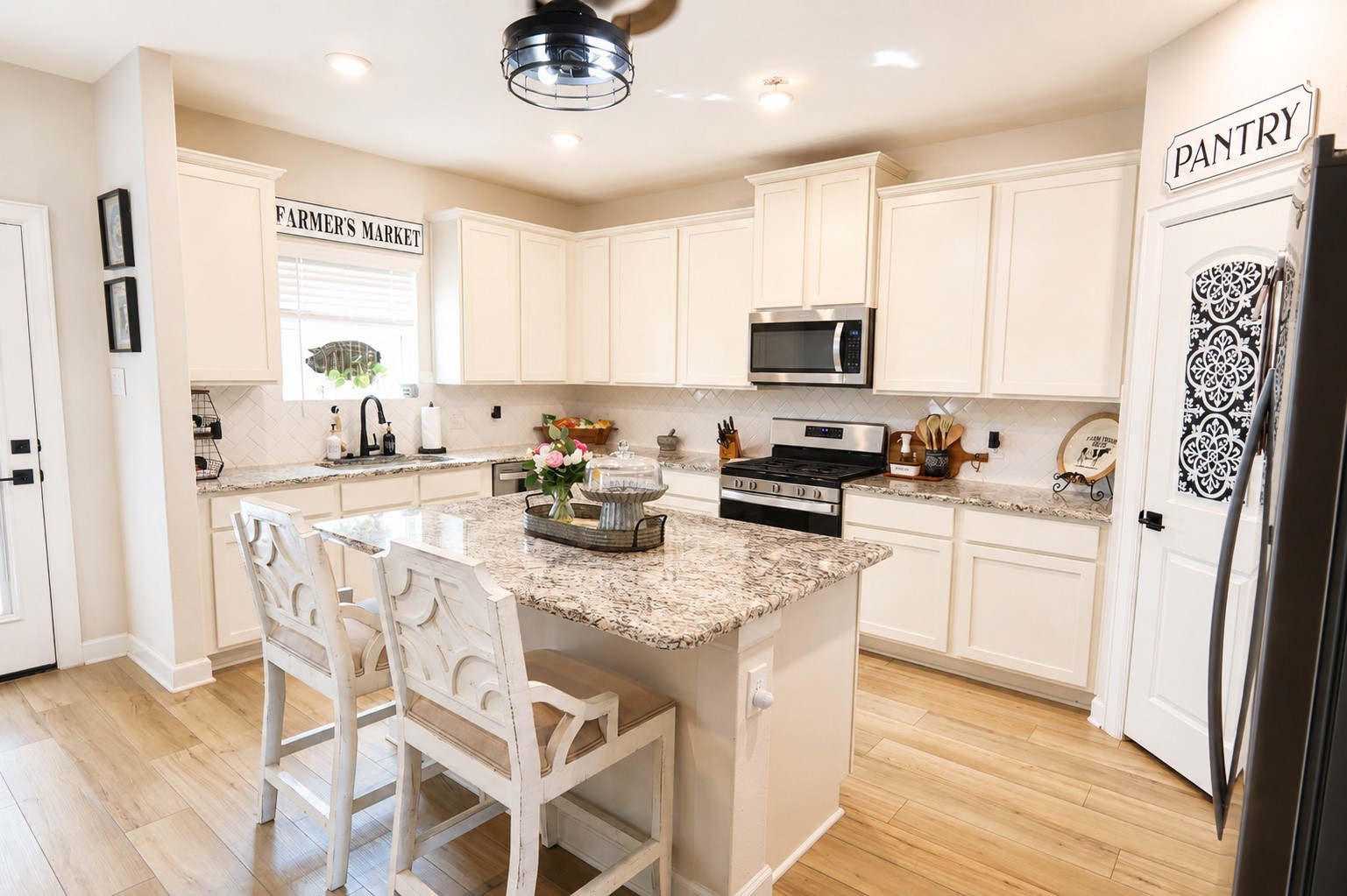 Bright, inviting kitchen featuring elegant granite countertops, modern stainless steel appliances, and ample cabinet space, complemented by warm laminate flooring and charming farmhouse accents.