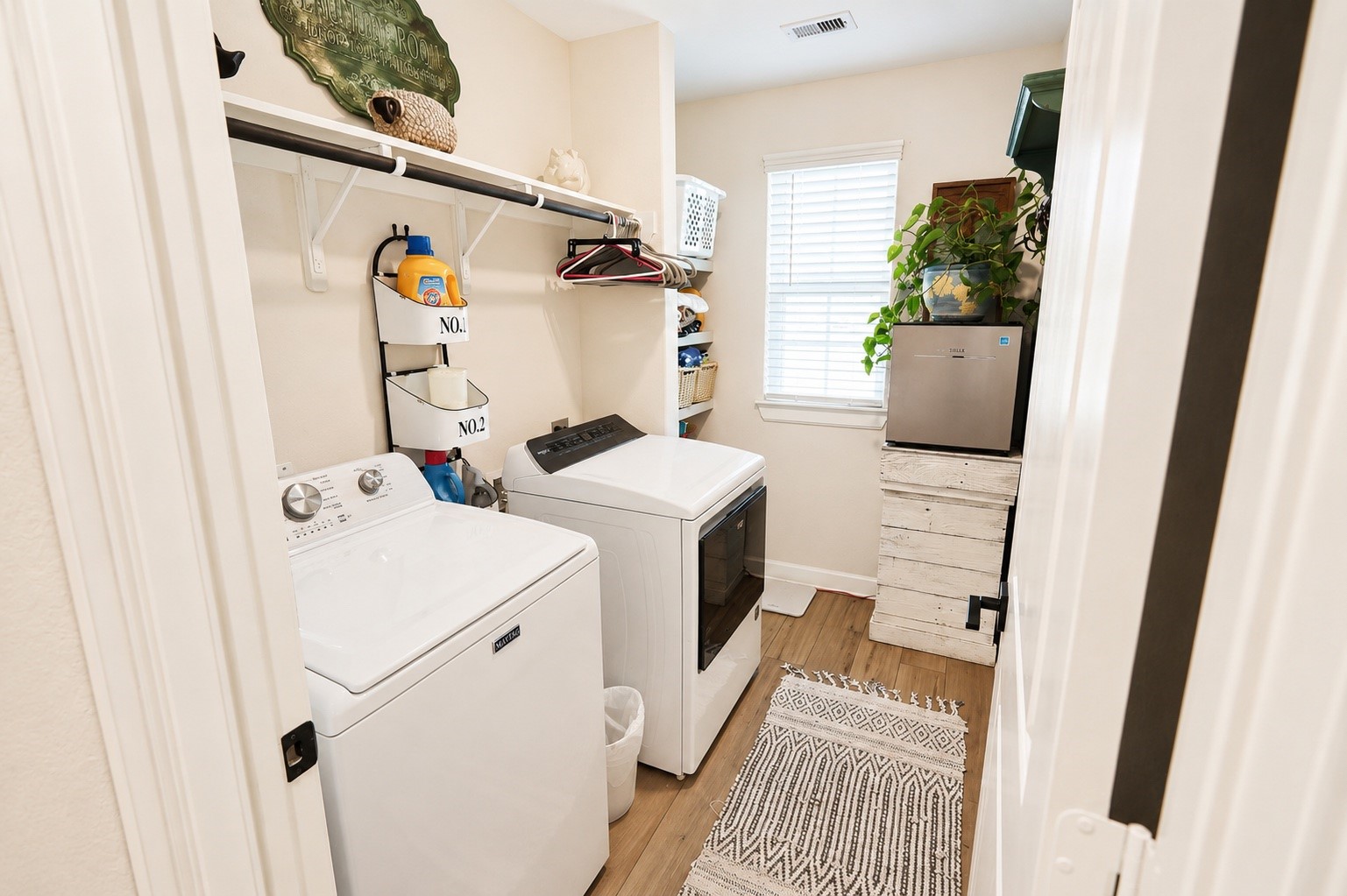 Bright and efficient laundry room featuring ample shelving, and natural light from a large window.