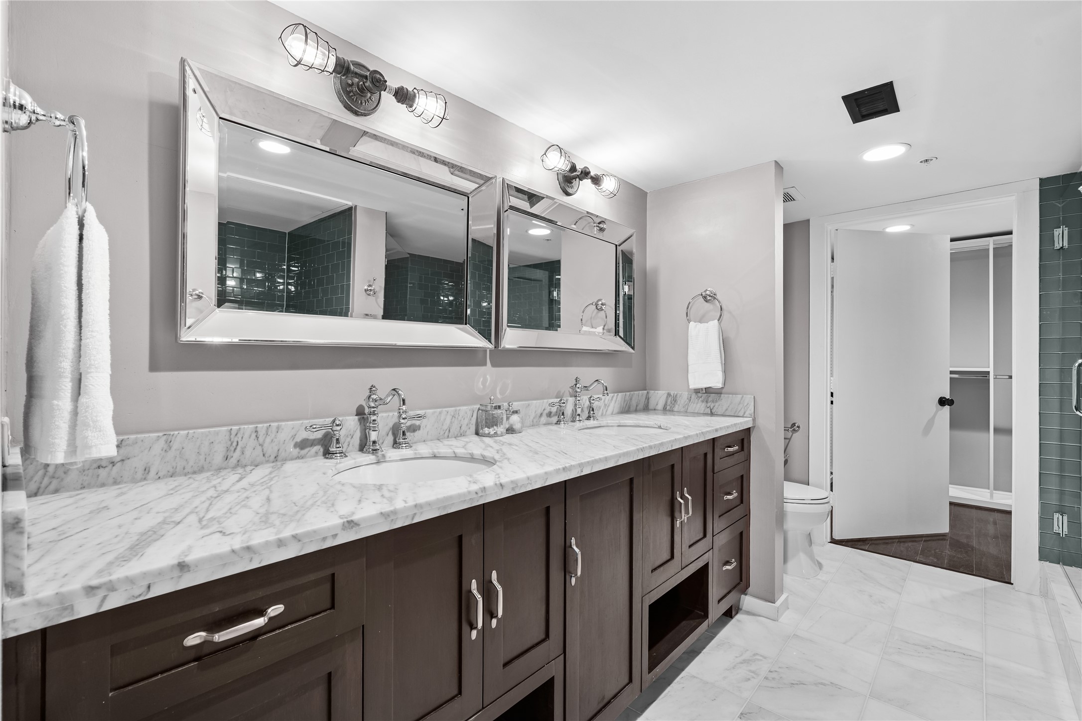 The completely remodeled primary bath offers a polished retreat with an expansive dual vanity, contemporary finishes and an oversized glass enclosed shower.