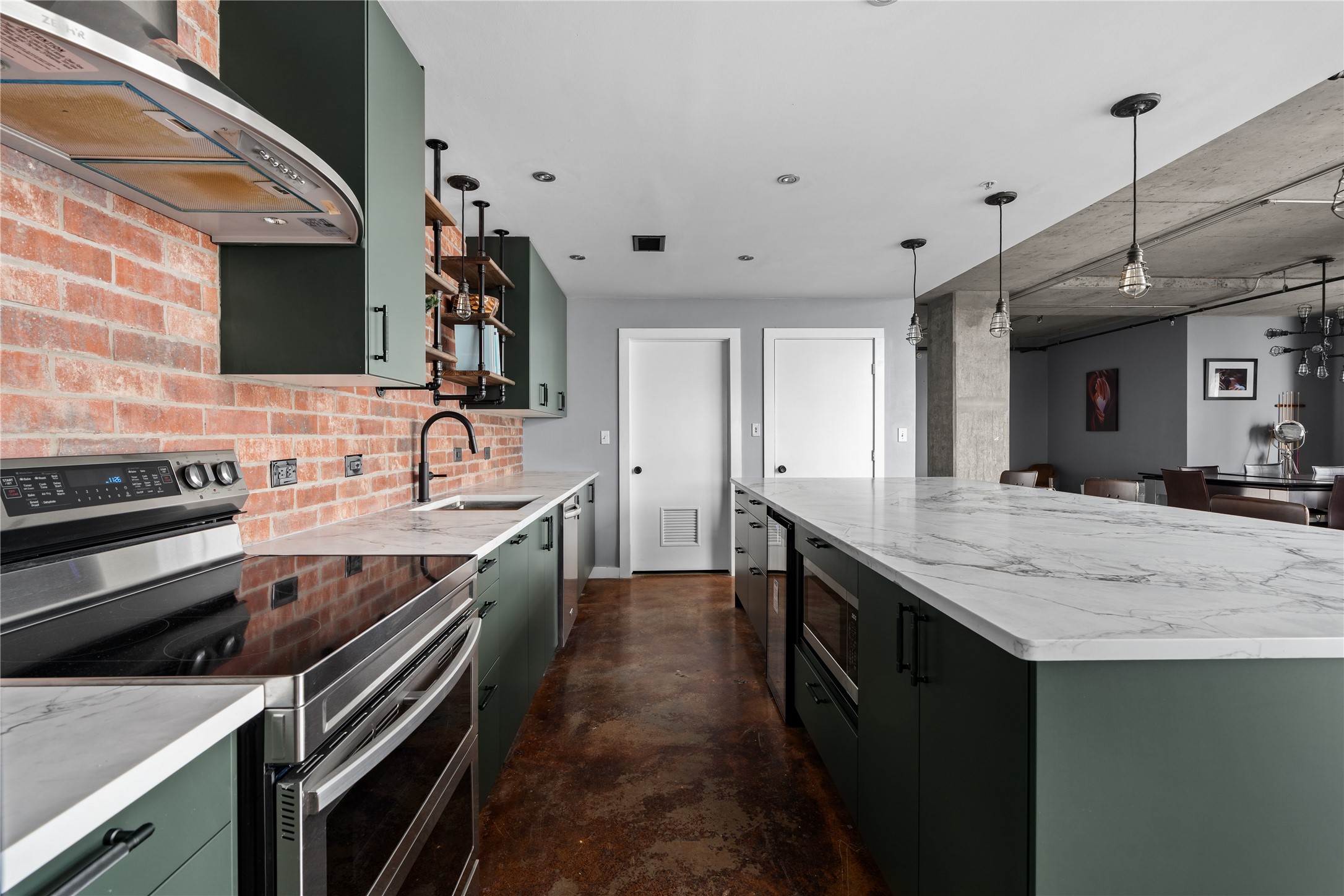 A closer look at the renovated kitchen reveals generous prep space, extensive cabinetry and a long island designed for gathering, all set against the lofts original exposed brick.