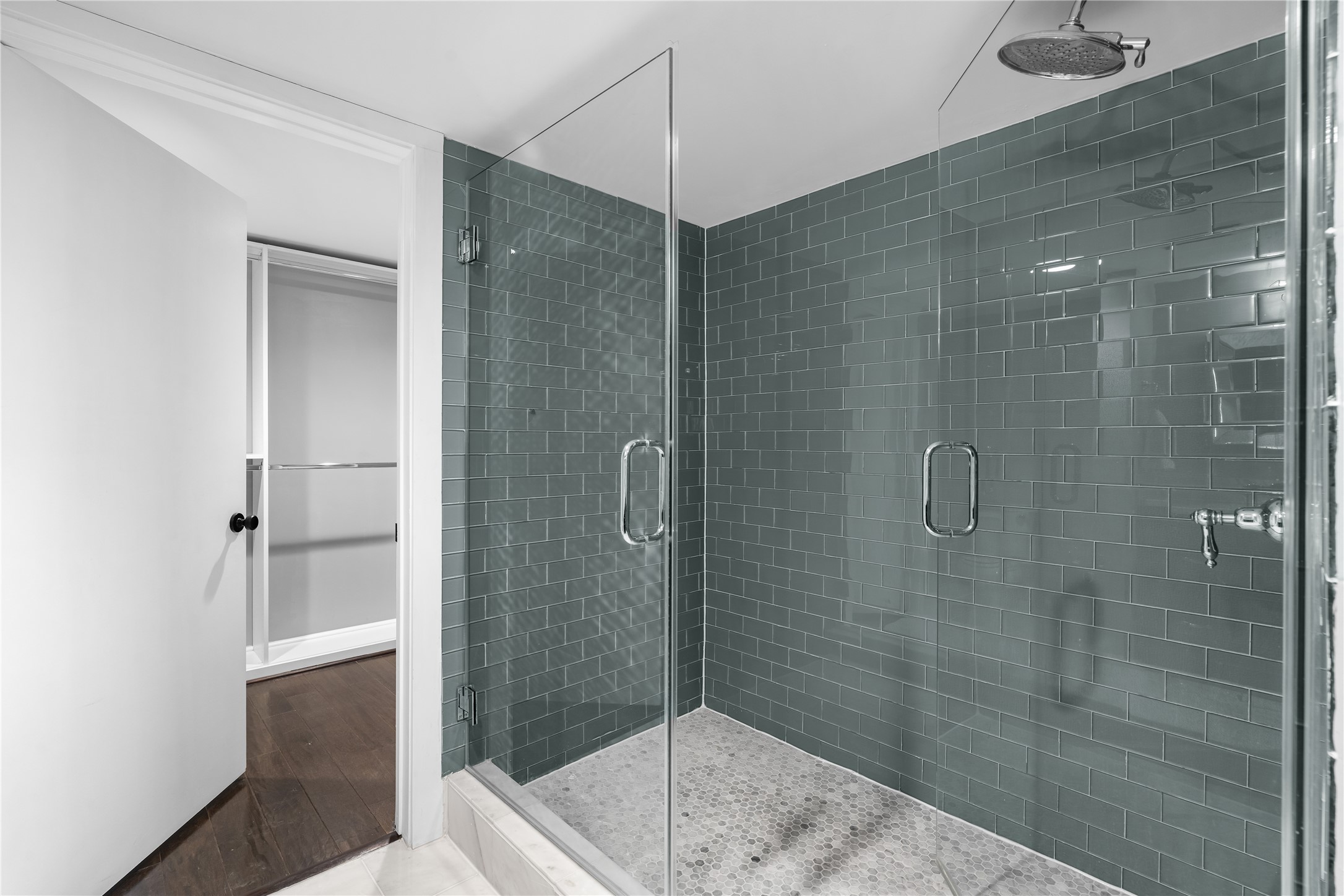 The oversized glass enclosed shower becomes a standout feature of the remodeled primary bath, finished with floor to ceiling tile and a clean, contemporary design.