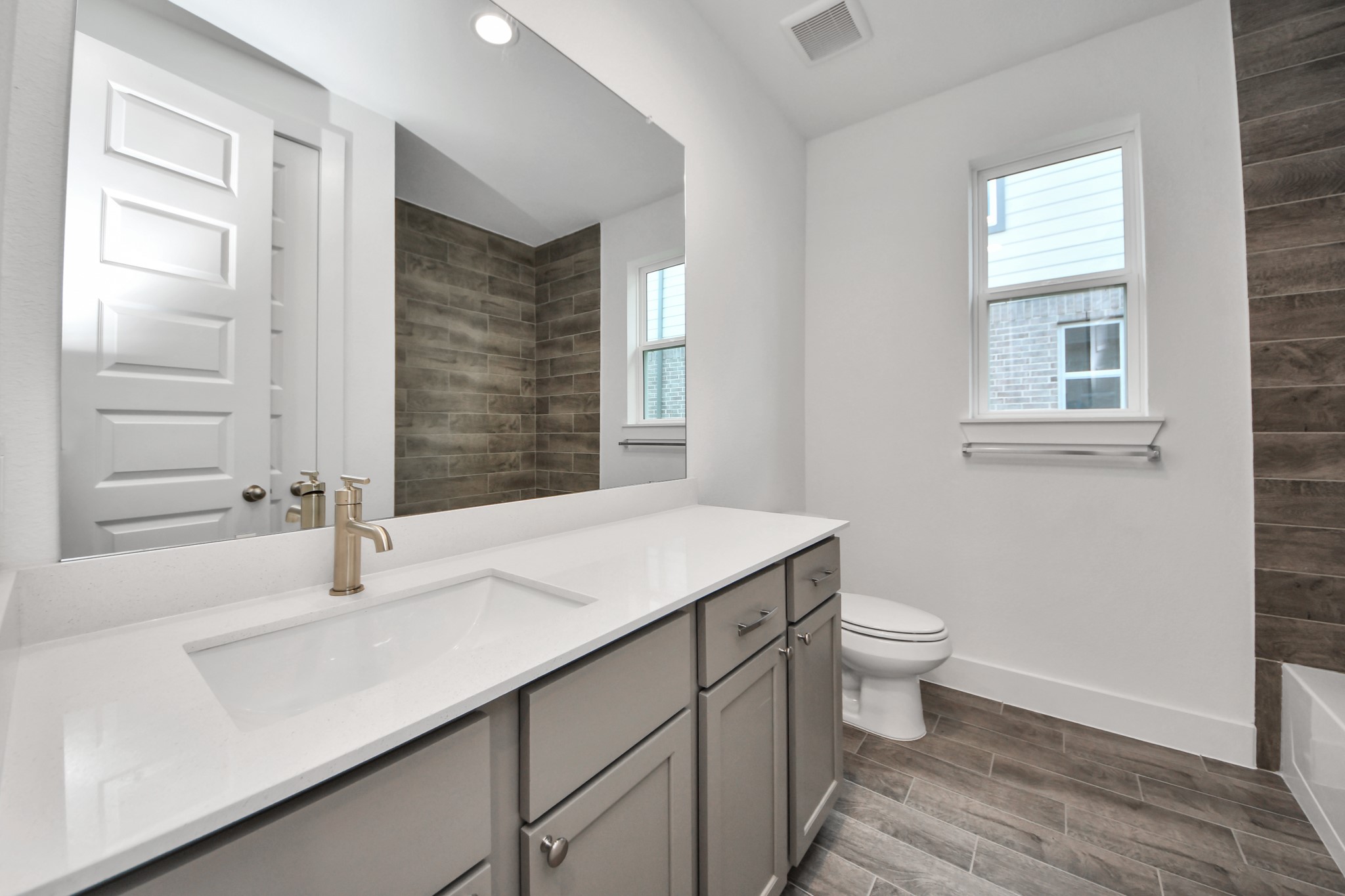 Secondary bath features tile flooring, bath/shower combo with tile surround, light stained wood cabinets, beautiful light countertop. Sample photo of completed home with similar floor plan. Actual colors and selections may vary.