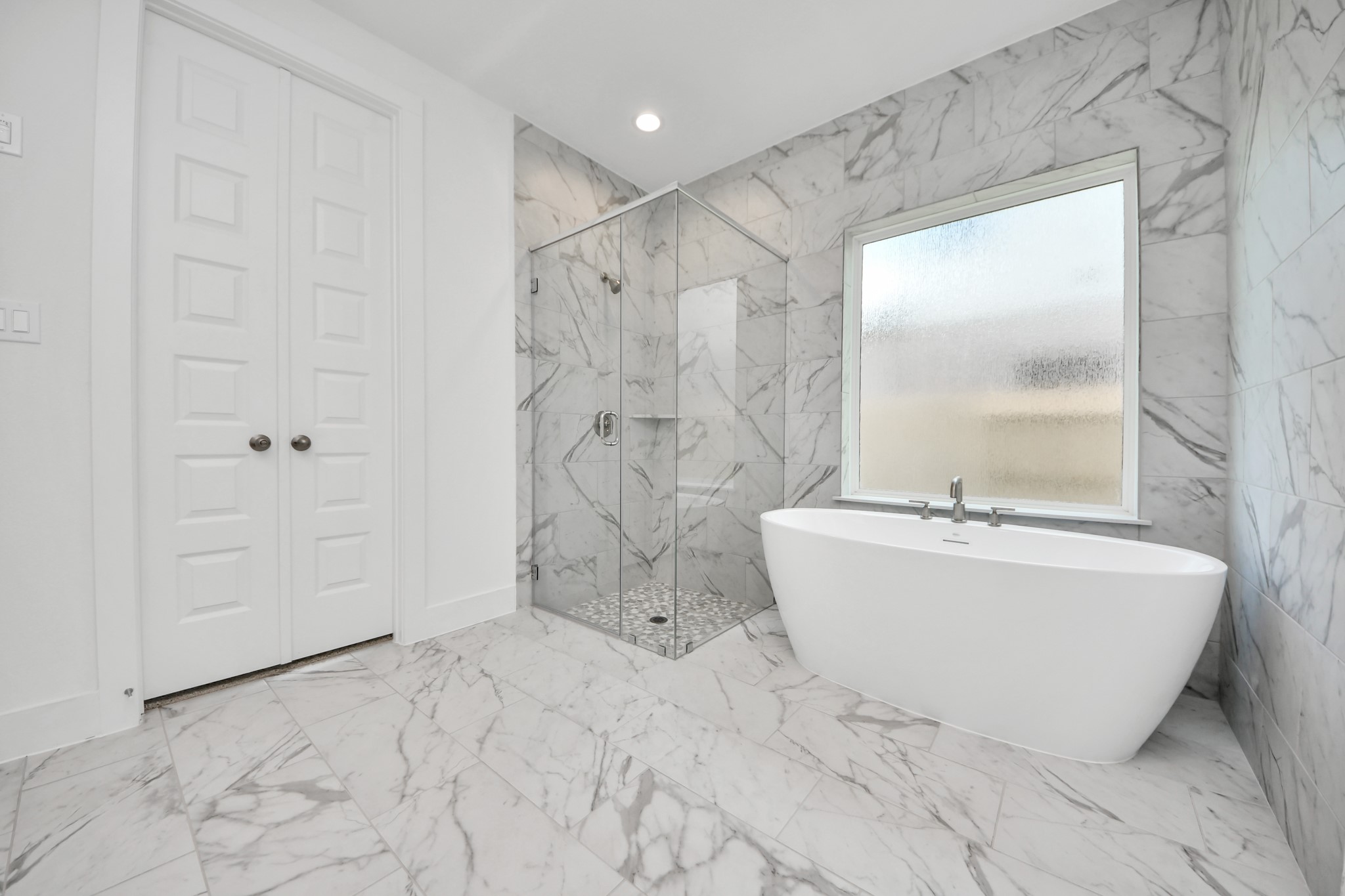 Indulge in a spa-like retreat within the confines of this primary bathroom. Delight in a spacious walk-in shower enveloped in stylish tile surround, unwind in a separate garden tub adorned with custom detailing. Sample photo of completed home with similar floor plan. Actual colors and selections may vary.