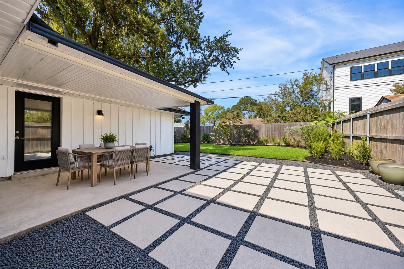 Contemporary concrete pavers and a covered patio set the stage for effortless outdoor entertaining. This photo has been virtually staged with outdoor furniture.