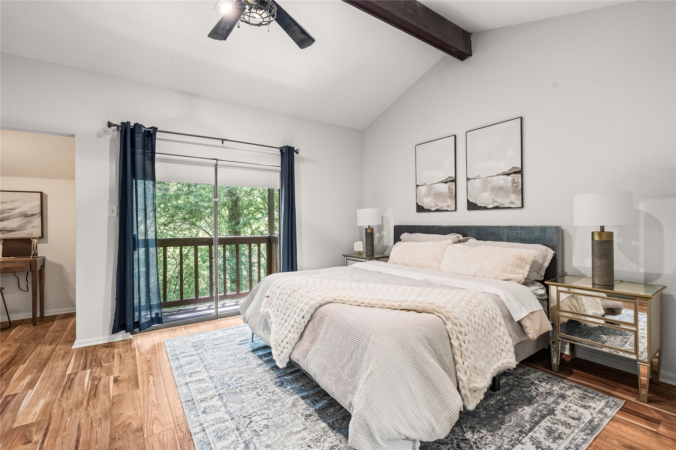Wake up to peaceful treetop views from your private balcony, all within a spacious primary suite highlighted by vaulted ceilings and an exposed wood beam.