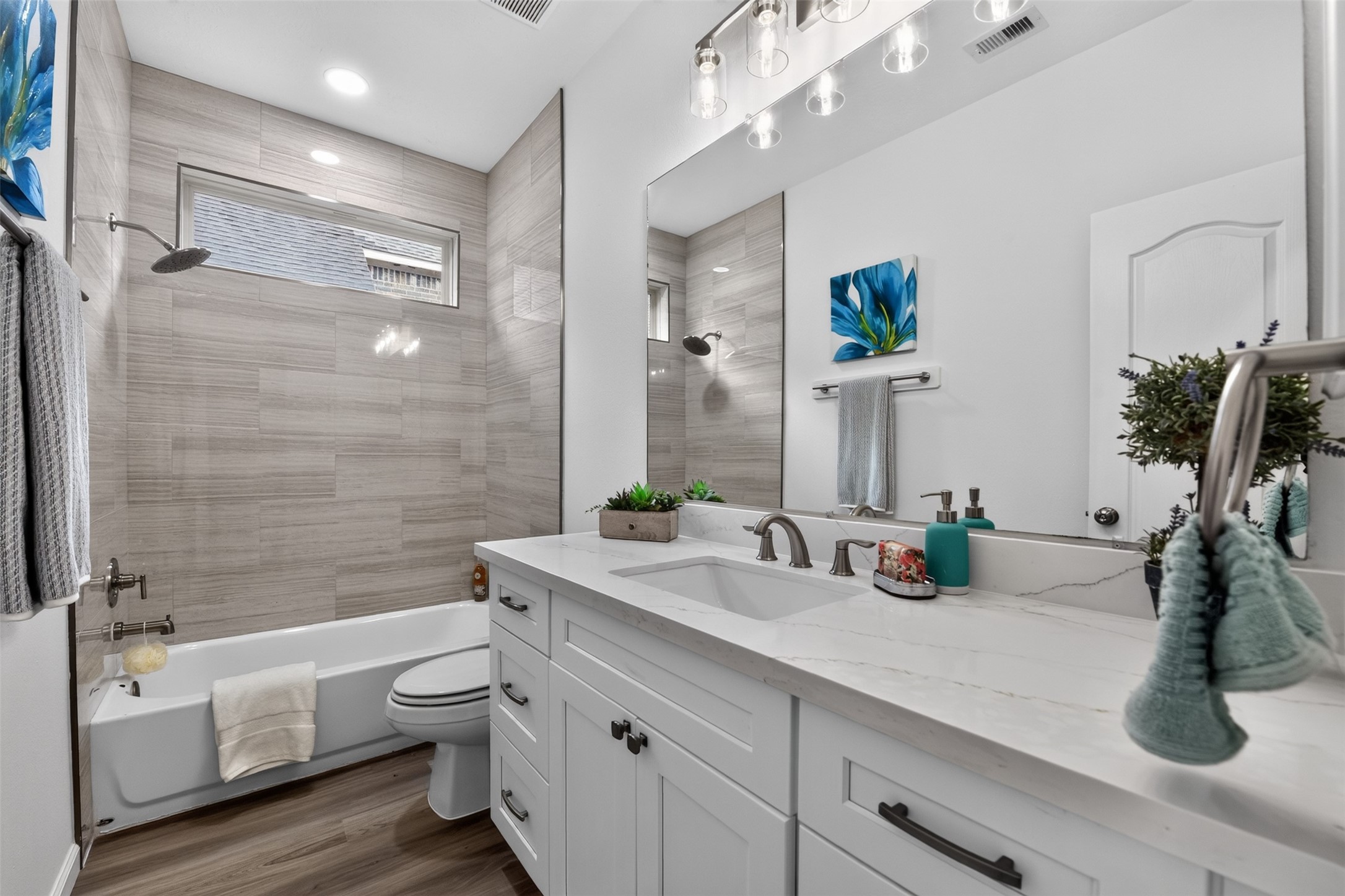 Secondary bathroom with new Quartz vanity, new shower tile and new lighting. New toilets and bathroom hardware throughout the home.