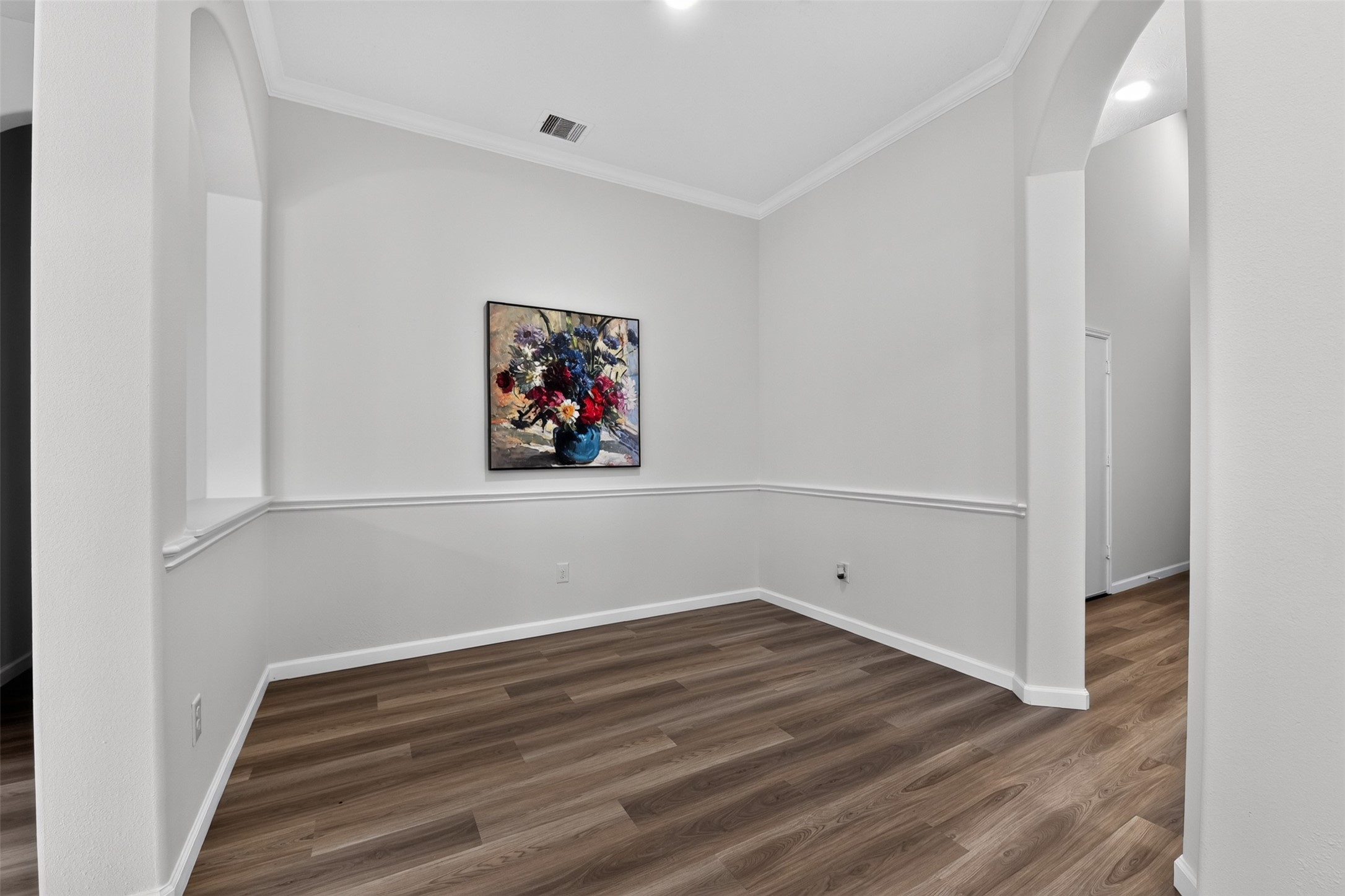 Formal dining room with arched opening to the living room and chair-rail molding.