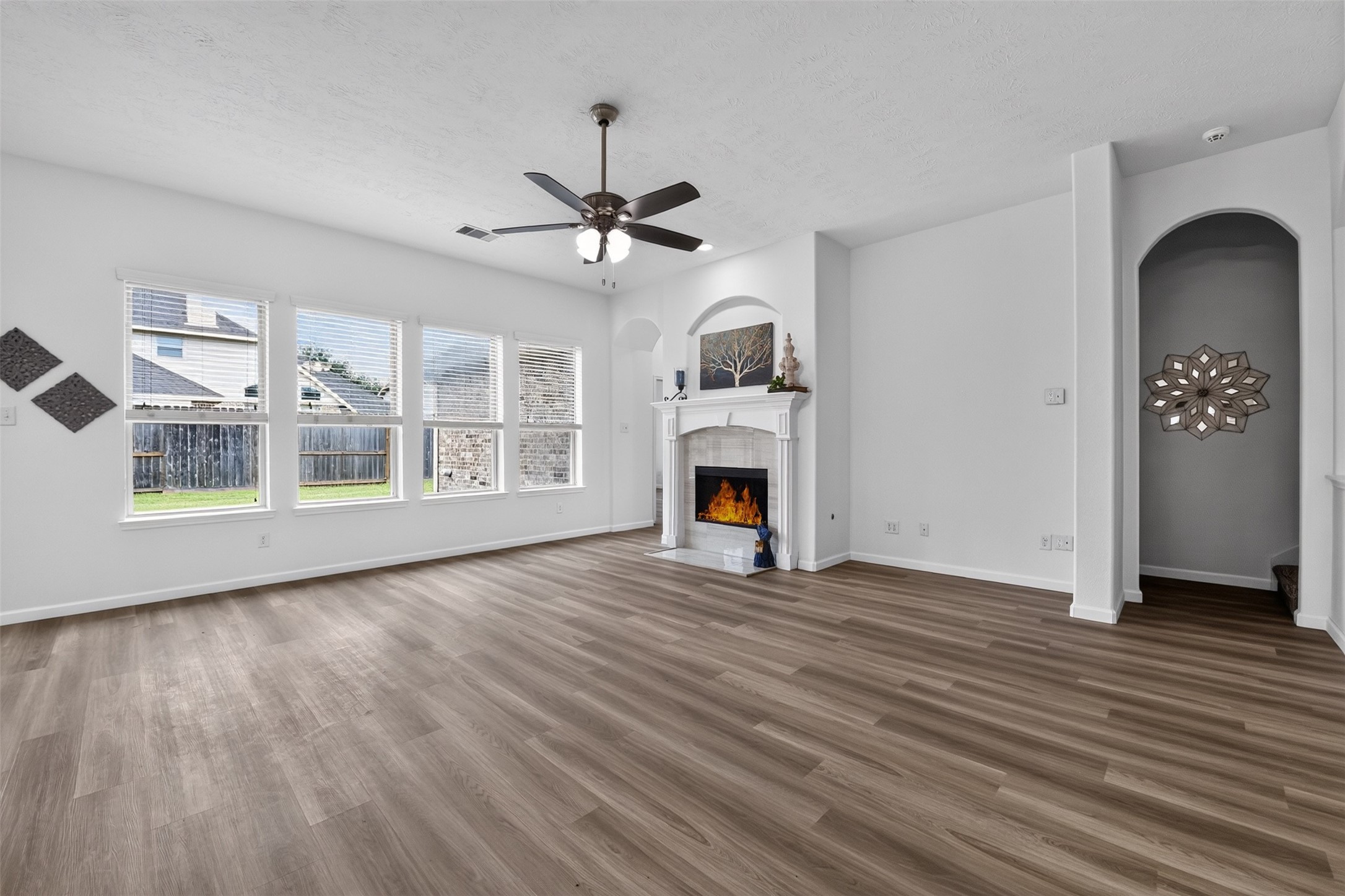 Another view of the living room with cozy fireplace, recessed wall and lighted ceiling fan. New ceiling fans throughout the home! Another view of the living room with cozy fireplace, recessed wall and lighted ceiling fan. New ceiling fans throughout the home!