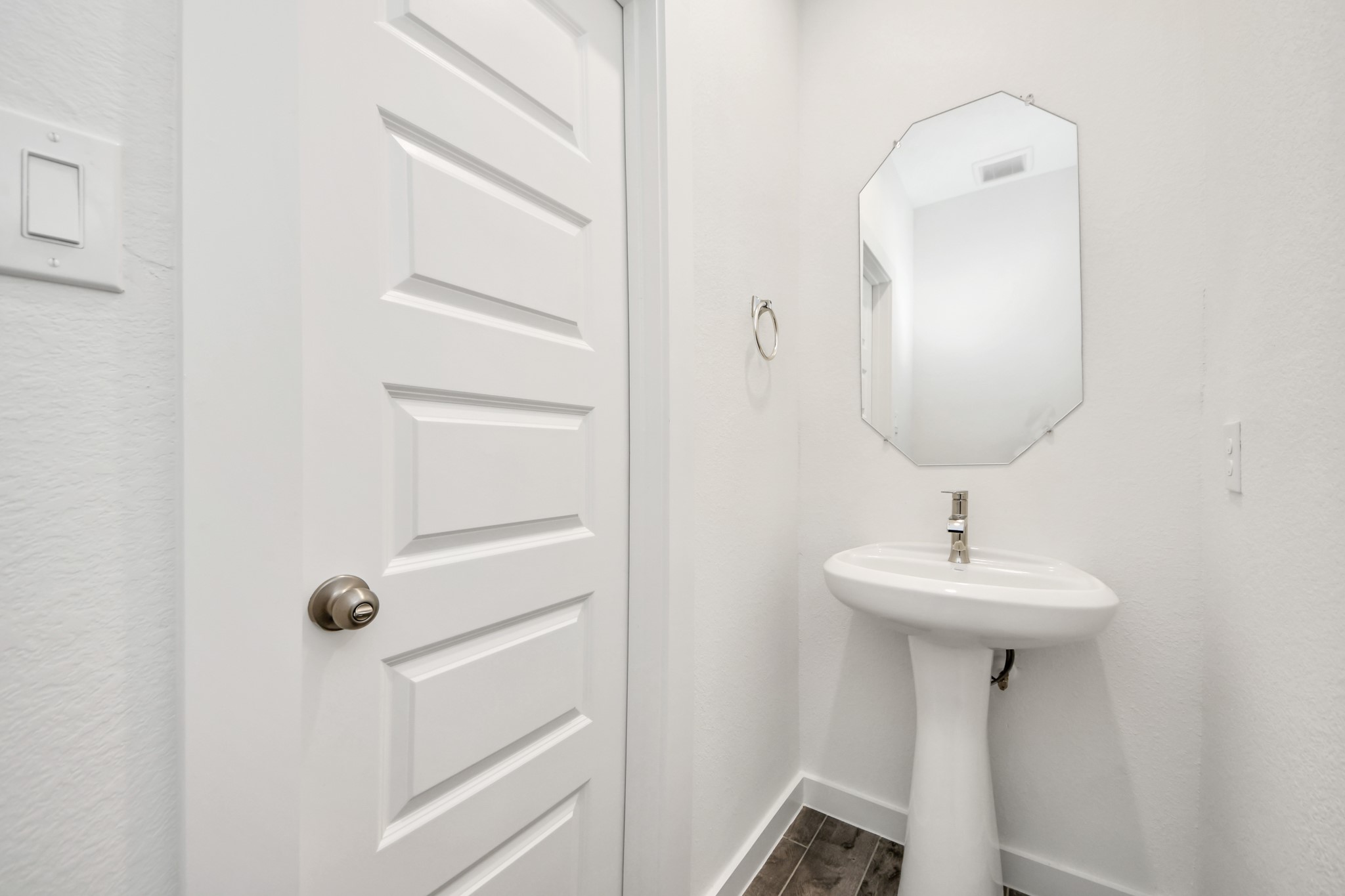 This half bathroom features a stylish pedestal sink, modern hardware, and bright recessed lighting, creating a sleek and inviting space. Sample photo of completed home with similar floor plan. Actual colors and selections may vary.