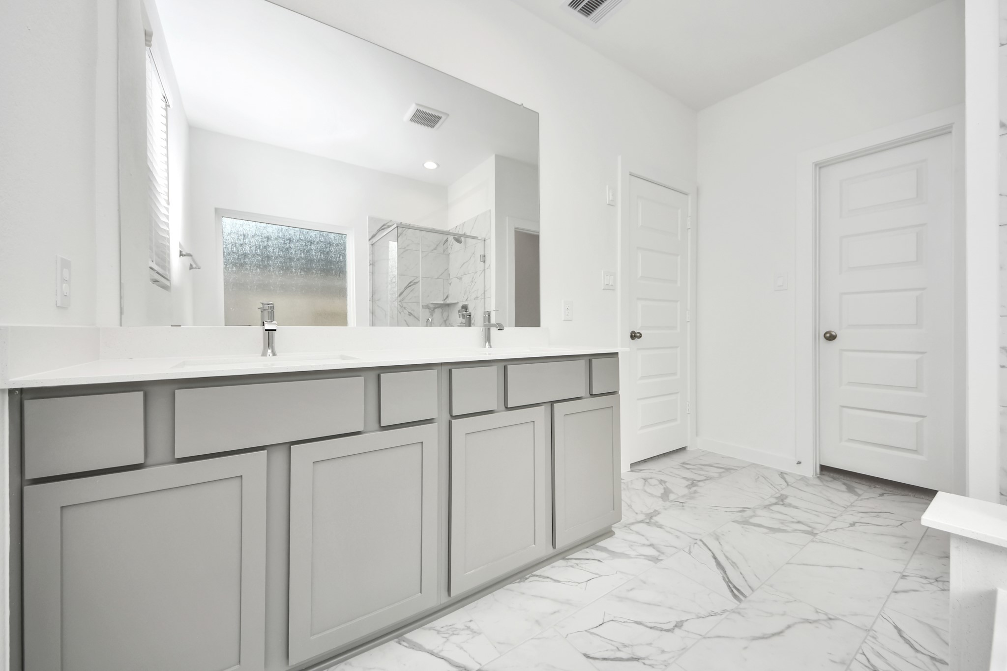 Elevate your daily routine at the elegant vanity, now equipped with double sinks, light countertops, modern hardware, and beautiful recessed lights. v
